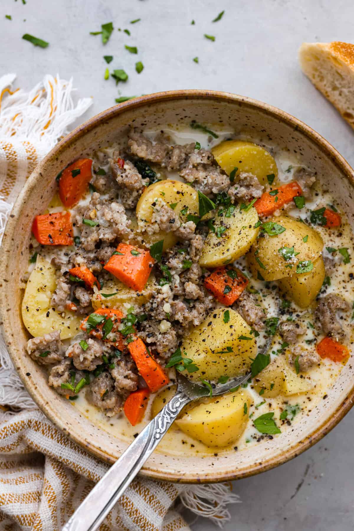 A serving of sausage and potato soup in a stoneware bowl.