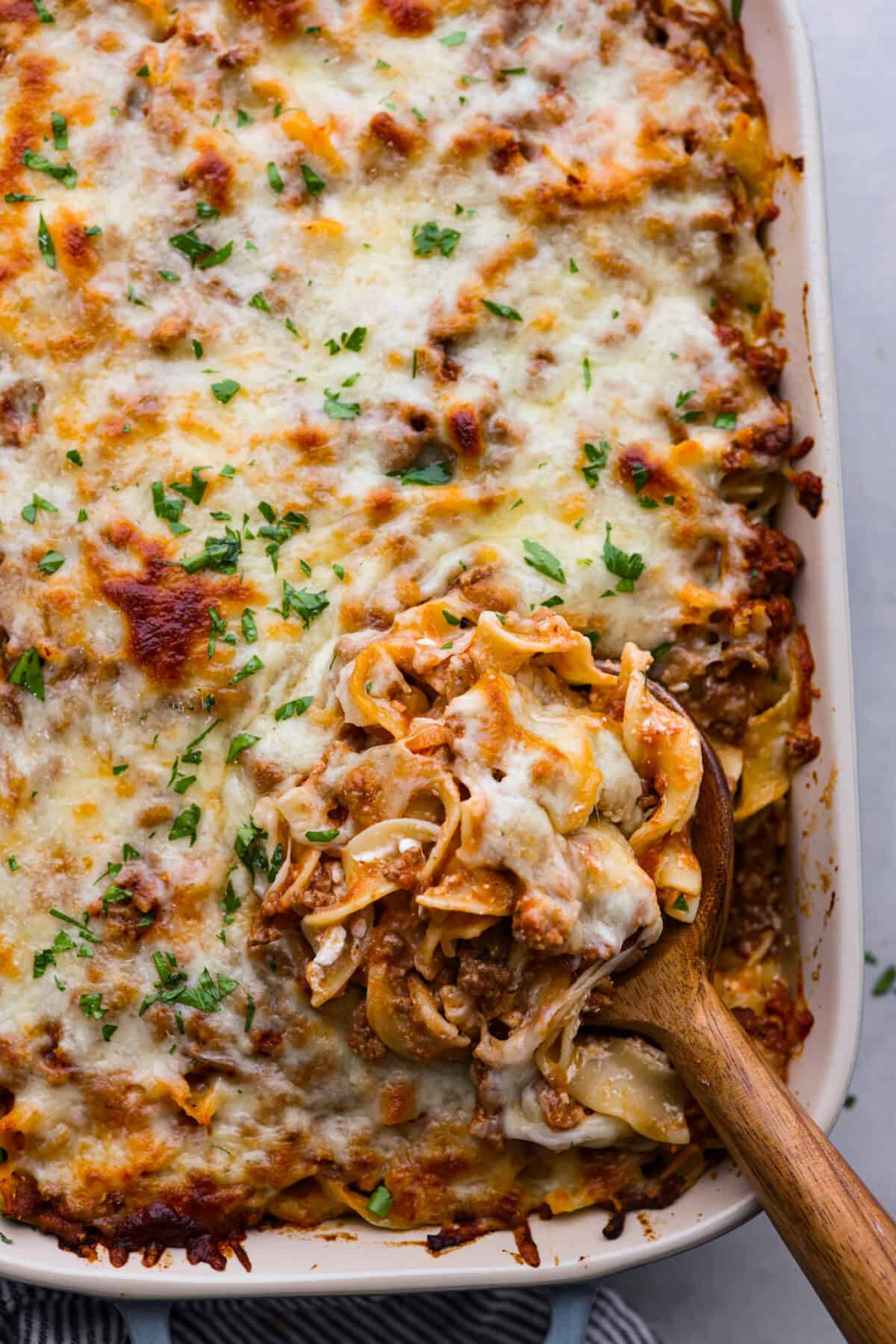 A scoop of sour cream noodle bake on a wooden spoon.