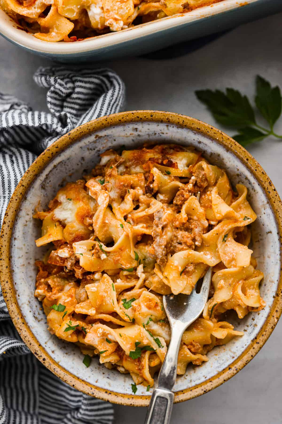 A serving of some sour cream noodle bake in a stoneware bowl.