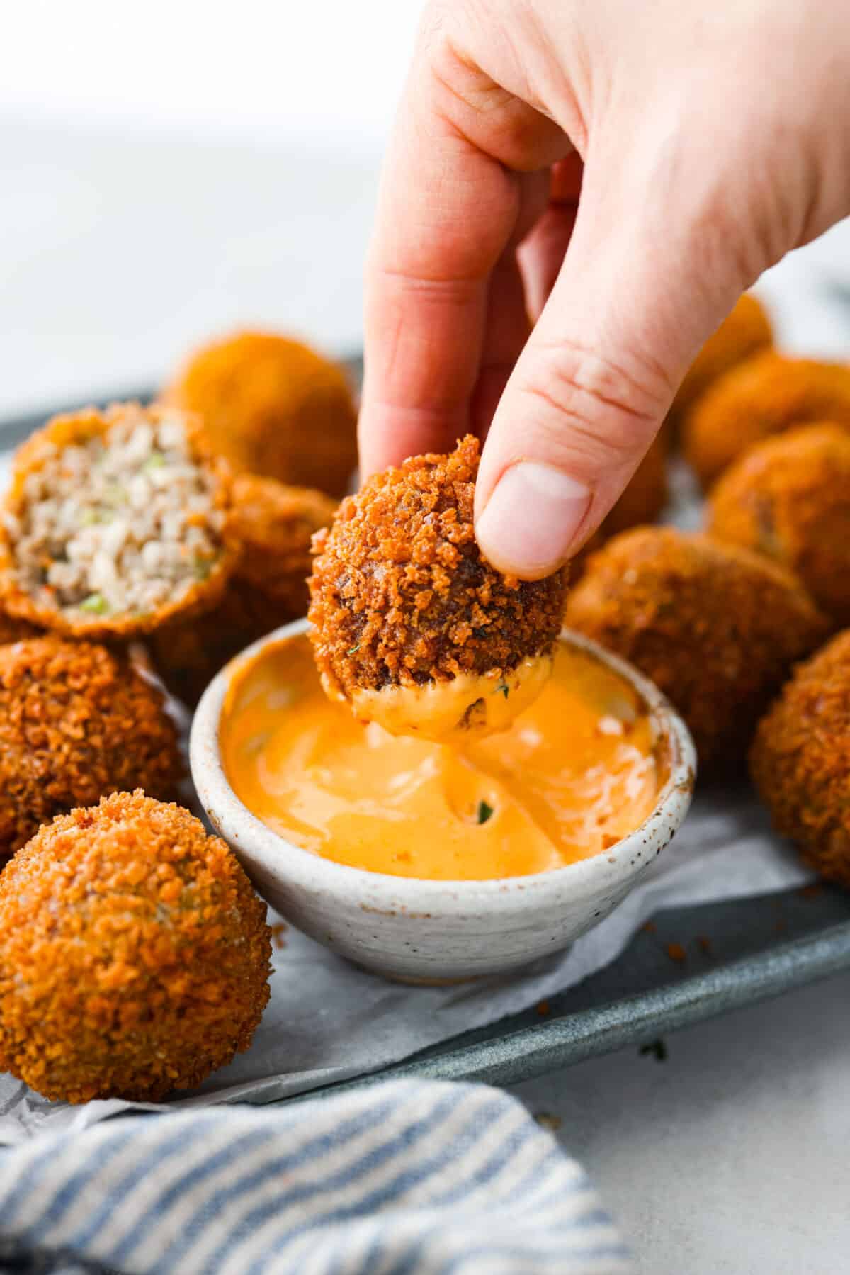 Close up shot of someone dipping a boudin ball in sauce. 