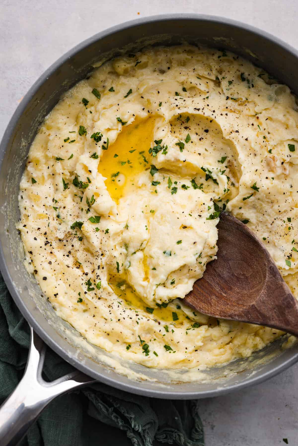 Top view of the Boursin mashed potatoes in a gray pot with a wooden serving spoon.