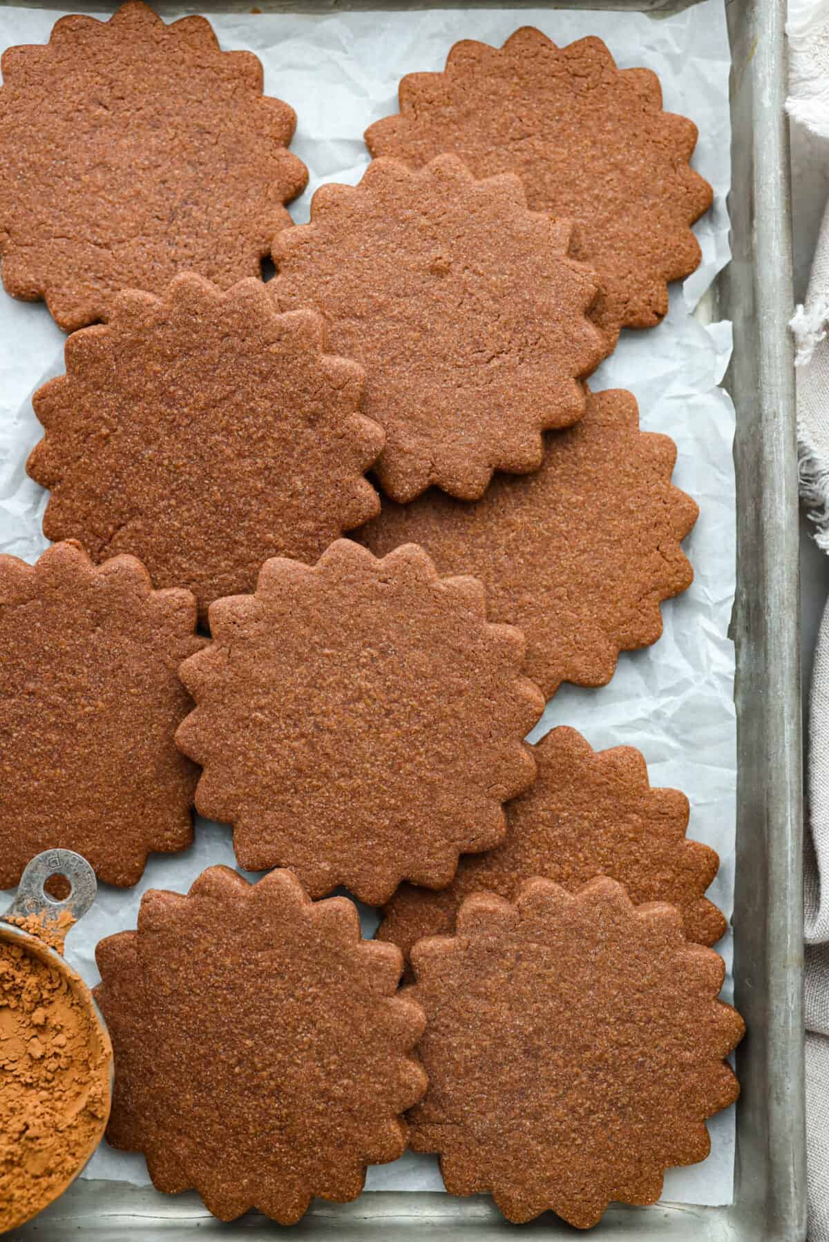 Top-down view of cooked chocolate sugar cookies in a parchment paper-lined pan.