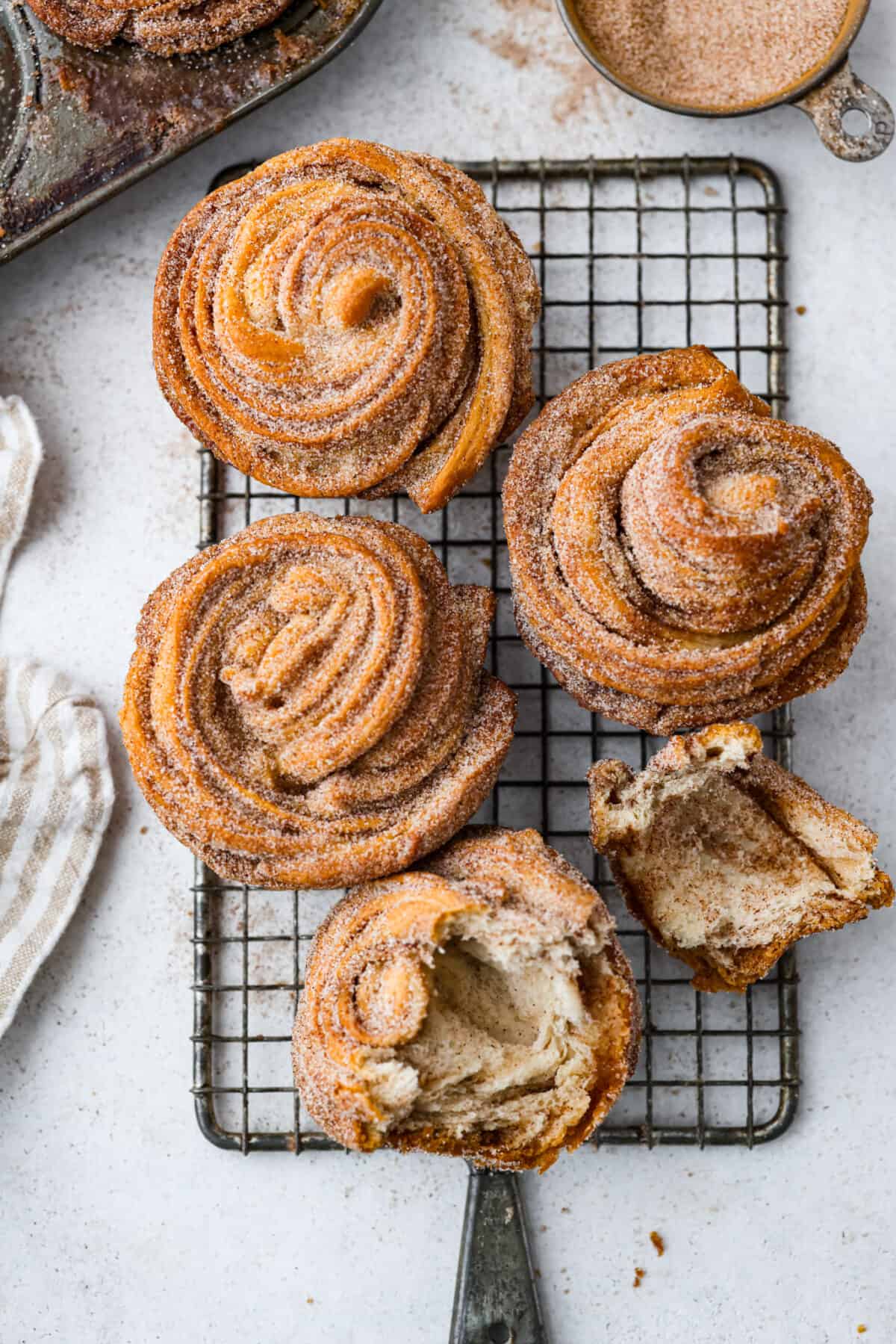 5 cruffins on a wire rack. One is torn in half.