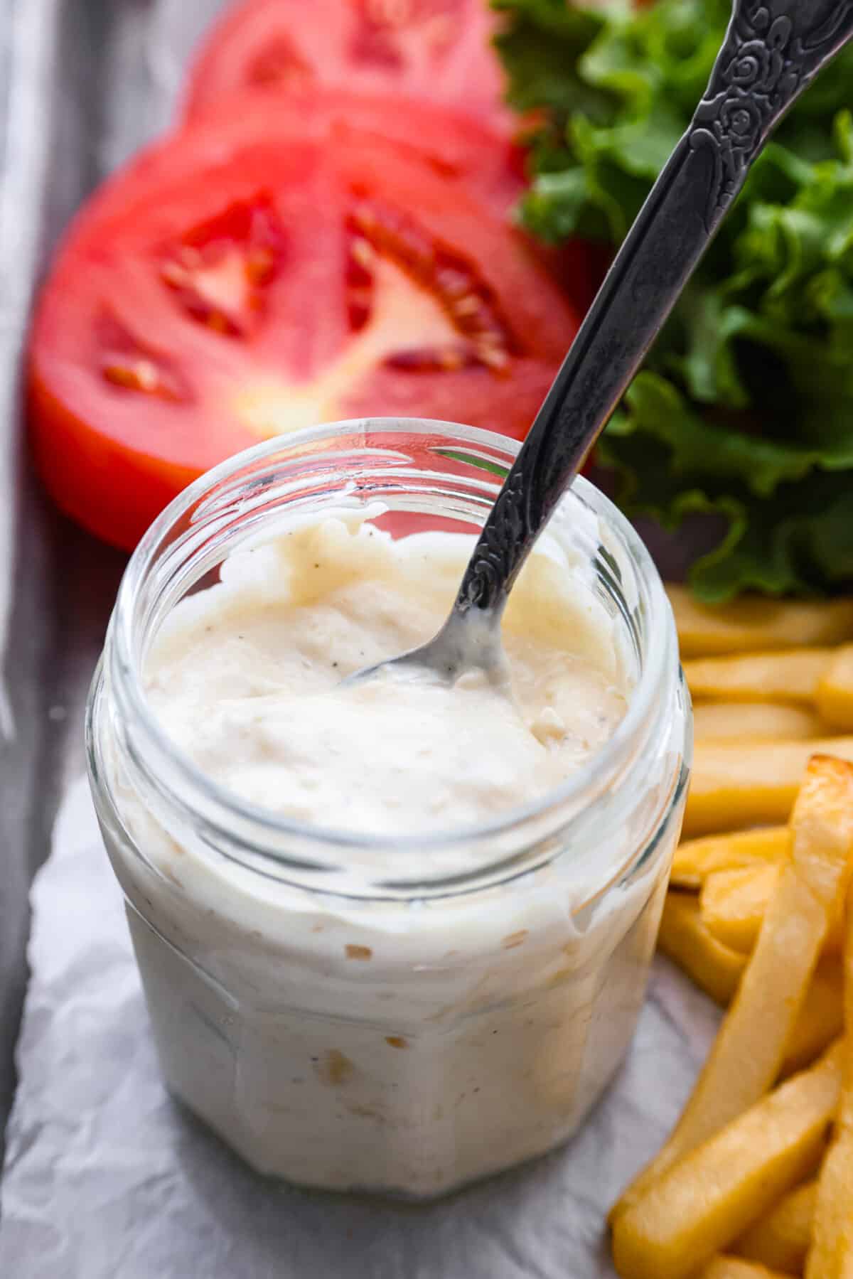 Close view of donkey sauce in a glass jar with a spoon.