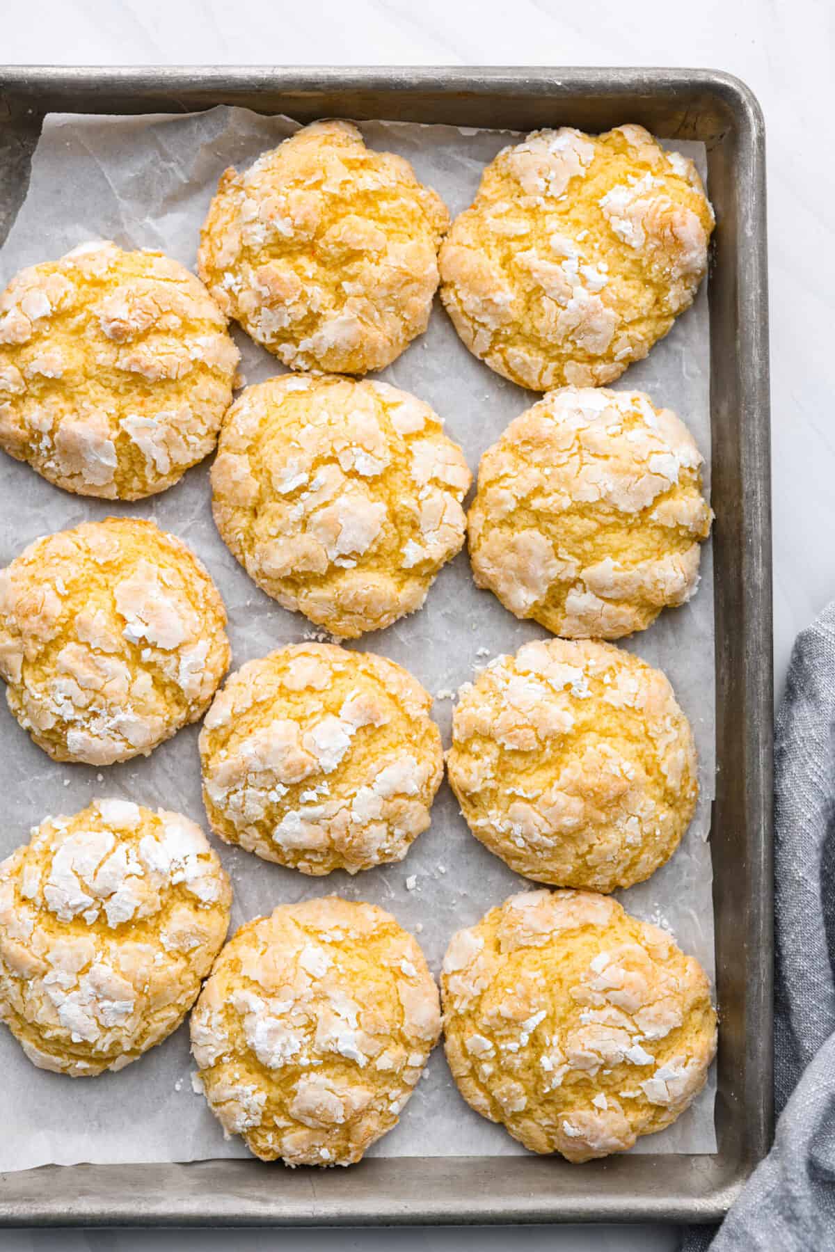 Top-down view of gooey butter cookies on a cookie sheet lined with parchment paper.