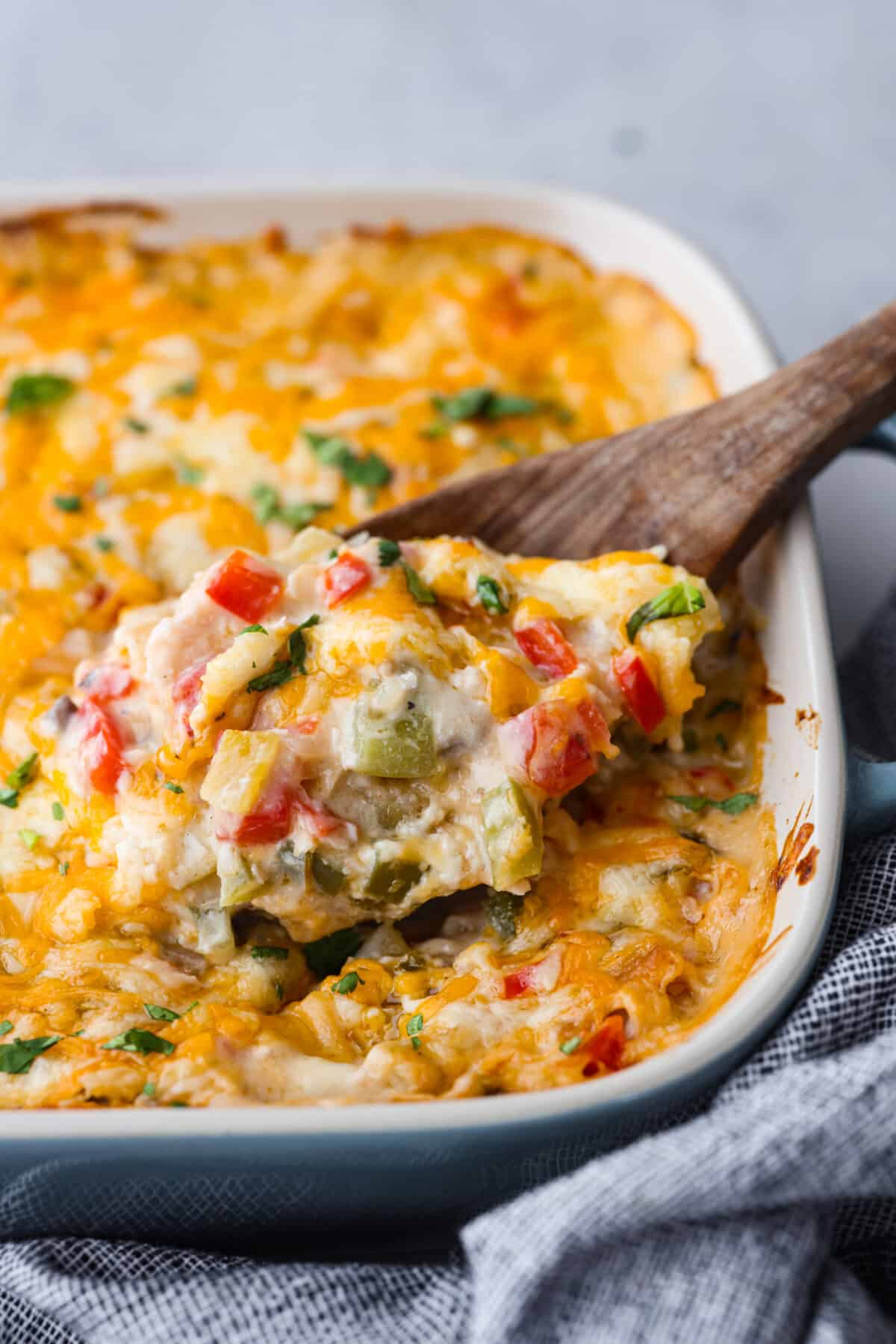 Close view of king ranch casserole in a baking dish with a wooden serving spoon.