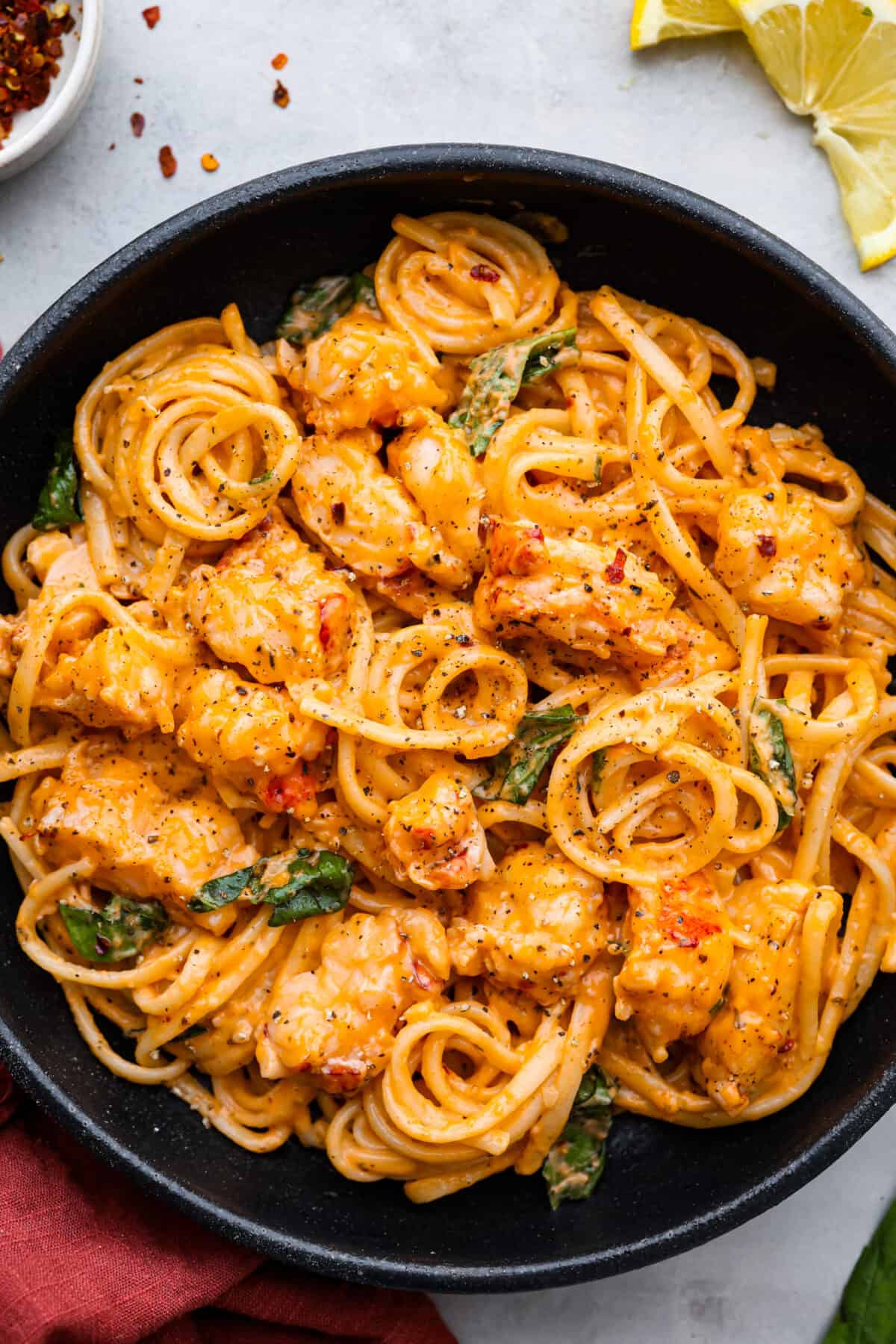 A serving of lobster pasta in a black bowl.