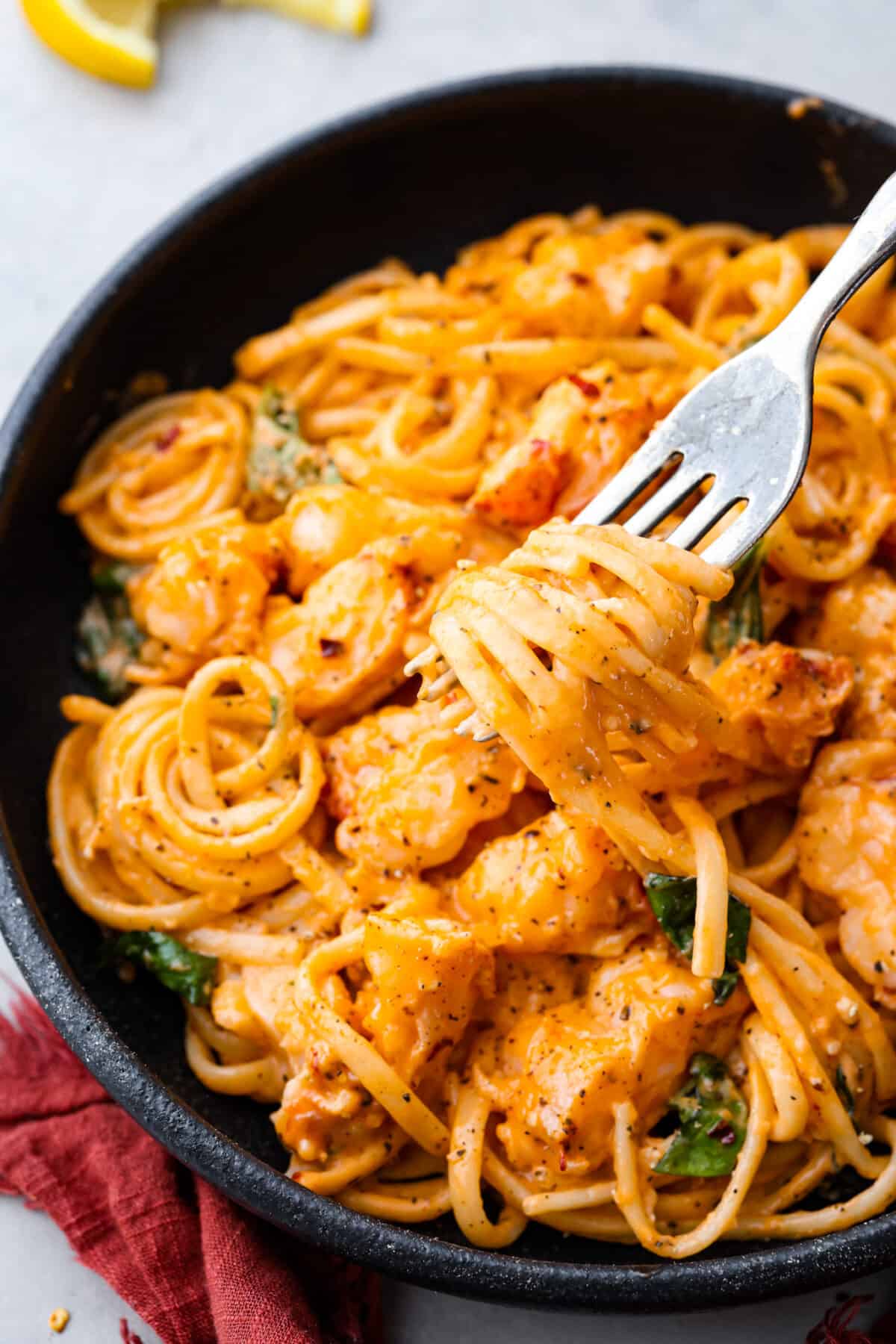 A bite of pasta twirled around a metal fork.