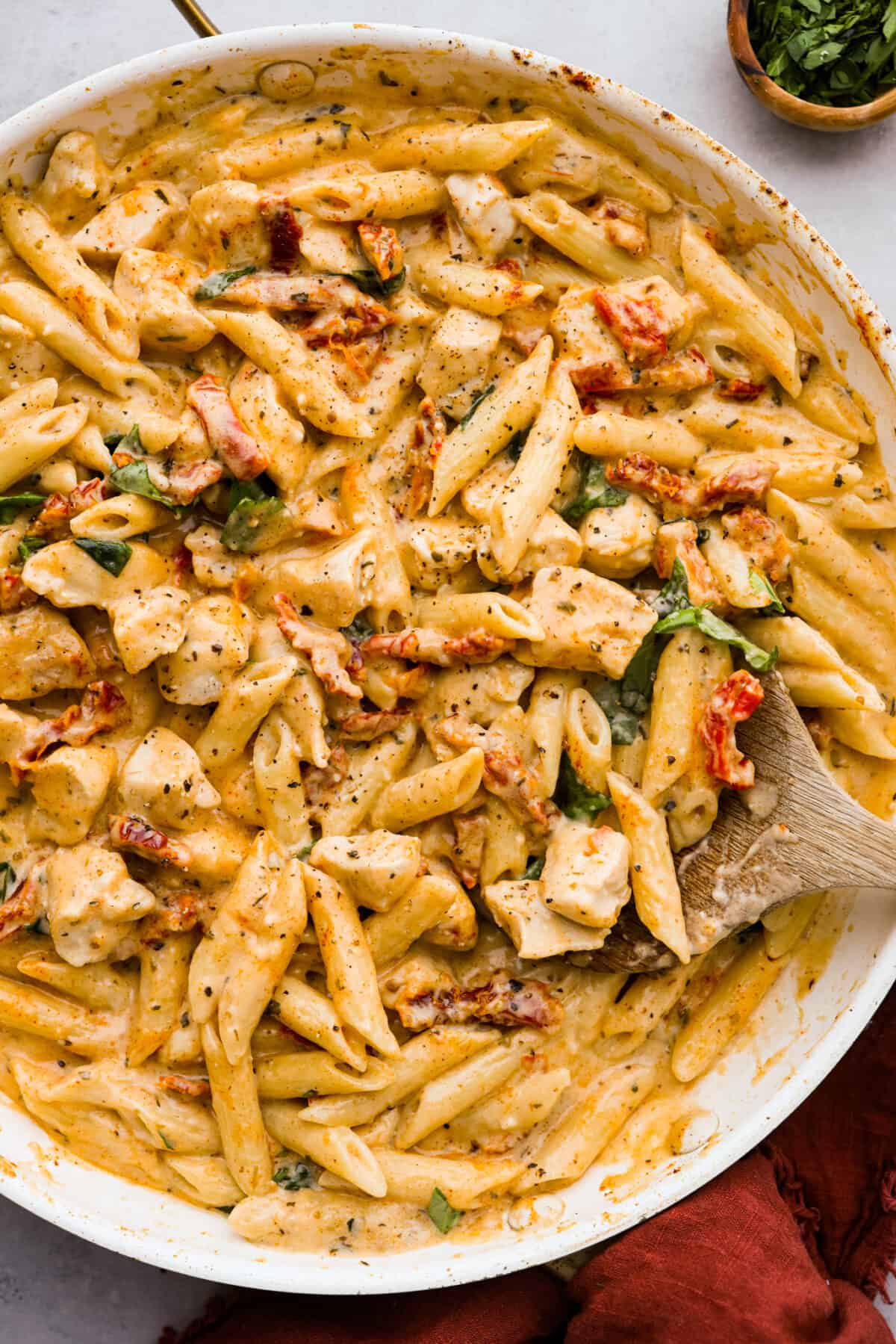 Top-down view of marry me chicken pasta in a white skillet.