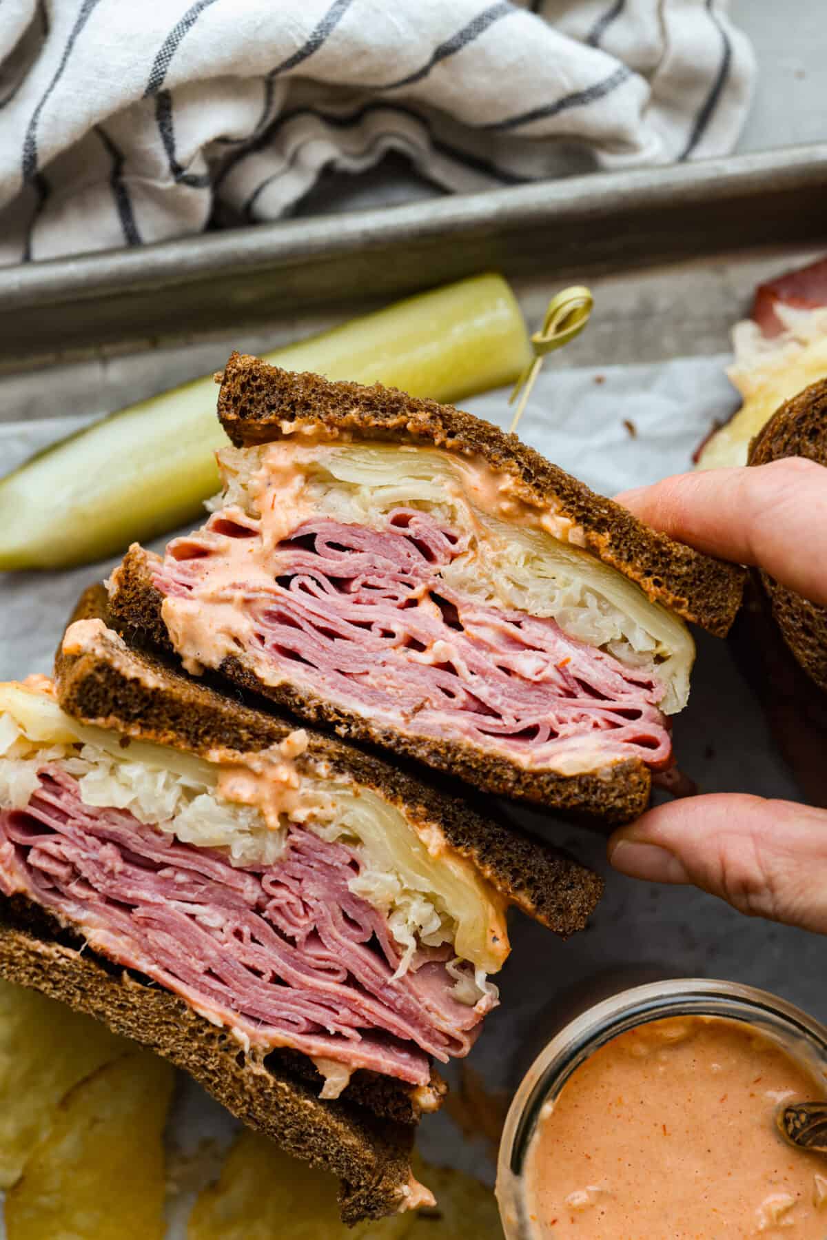 A sandwich cut in half, so the corned beef, sauerkraut, and swiss cheese filling can be seen.