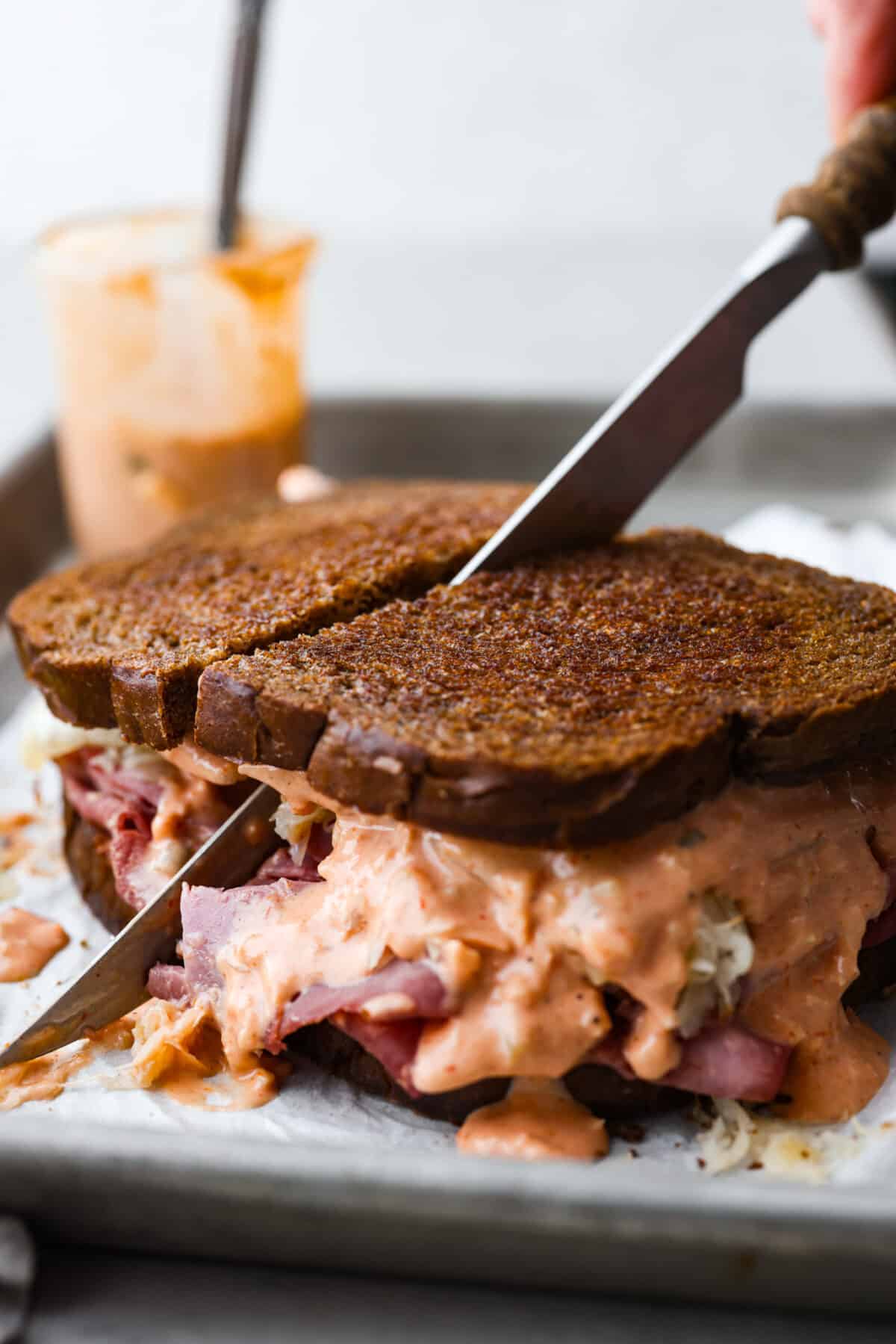 Cutting a sandwich made with Russian dressing in half.