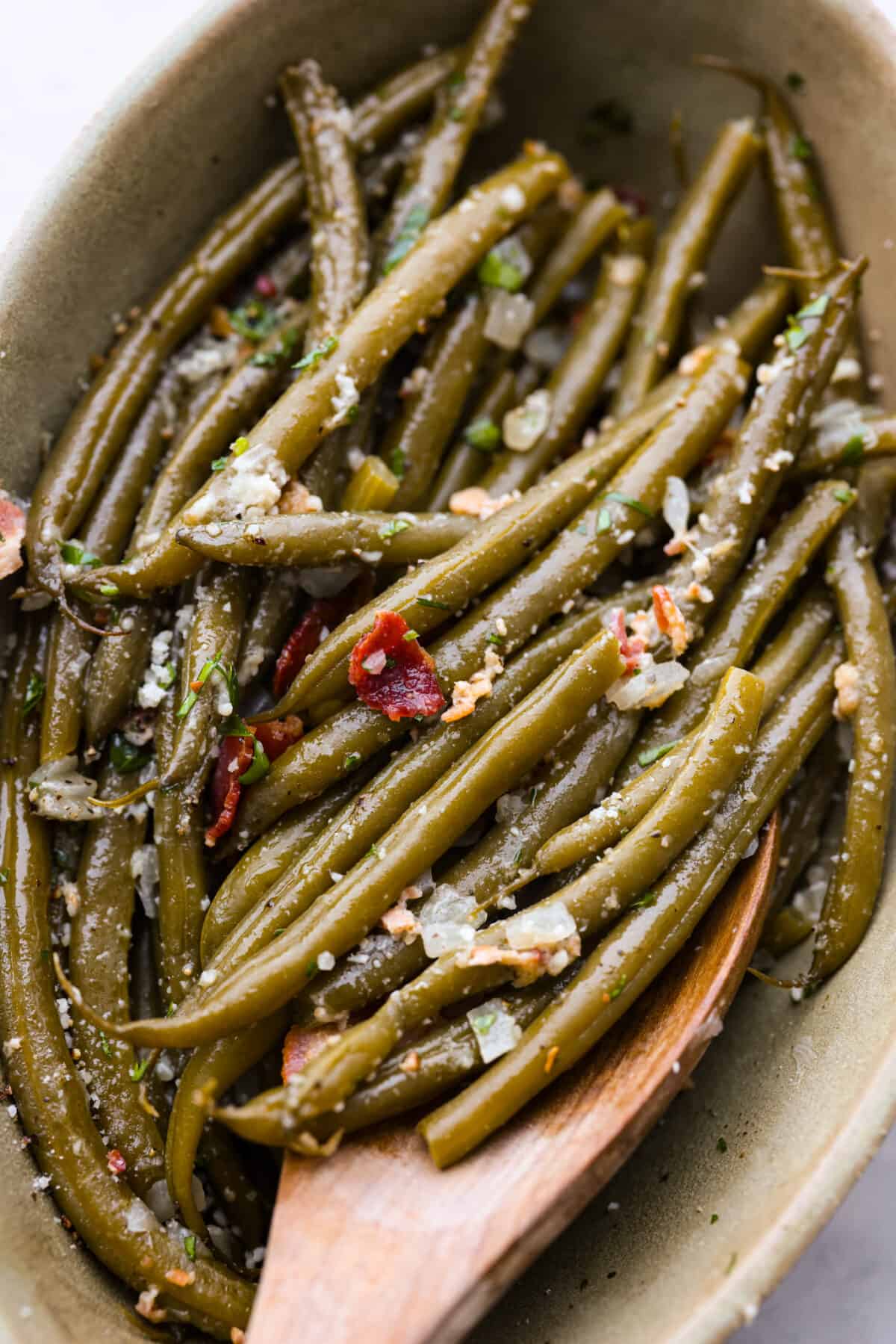 Scooping up the green beans with a wooden spoon.