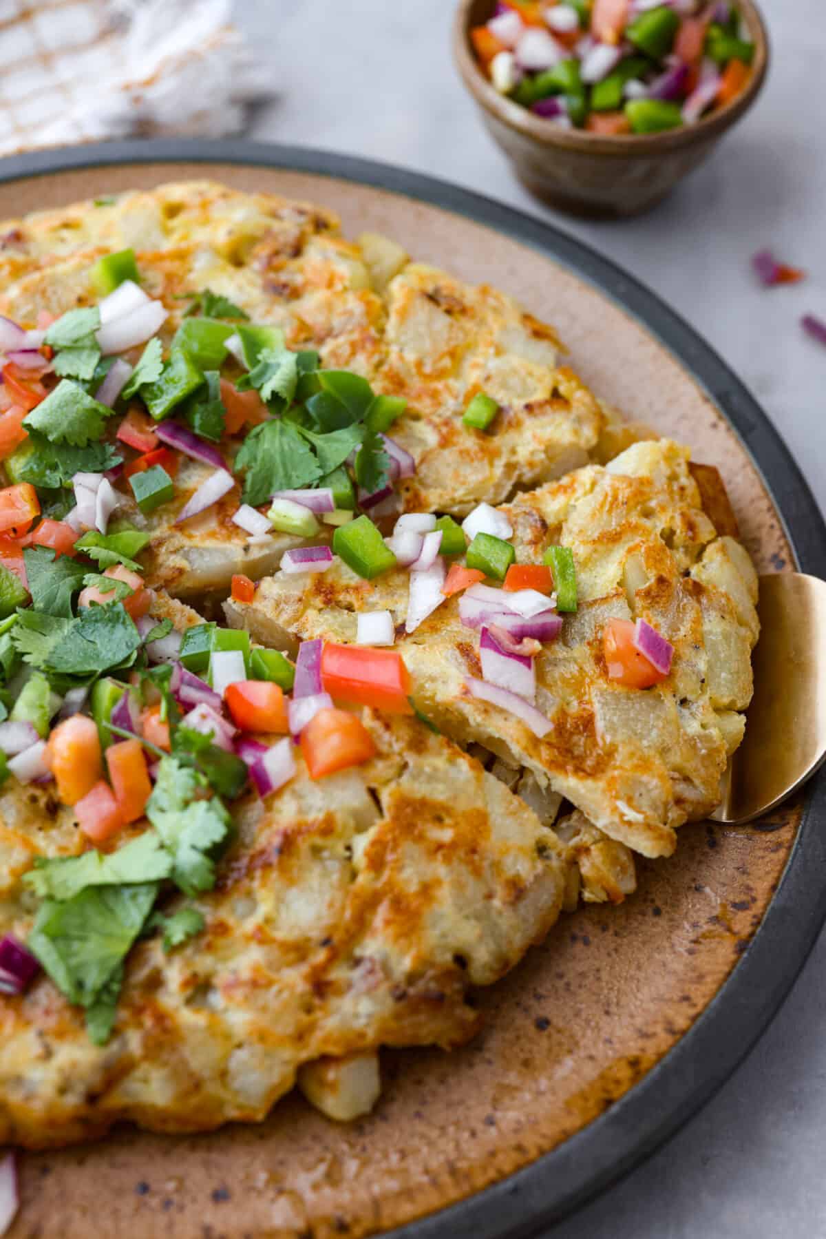 Close view of Spanish tortilla on a large plate garnished with salsa and cilantro.