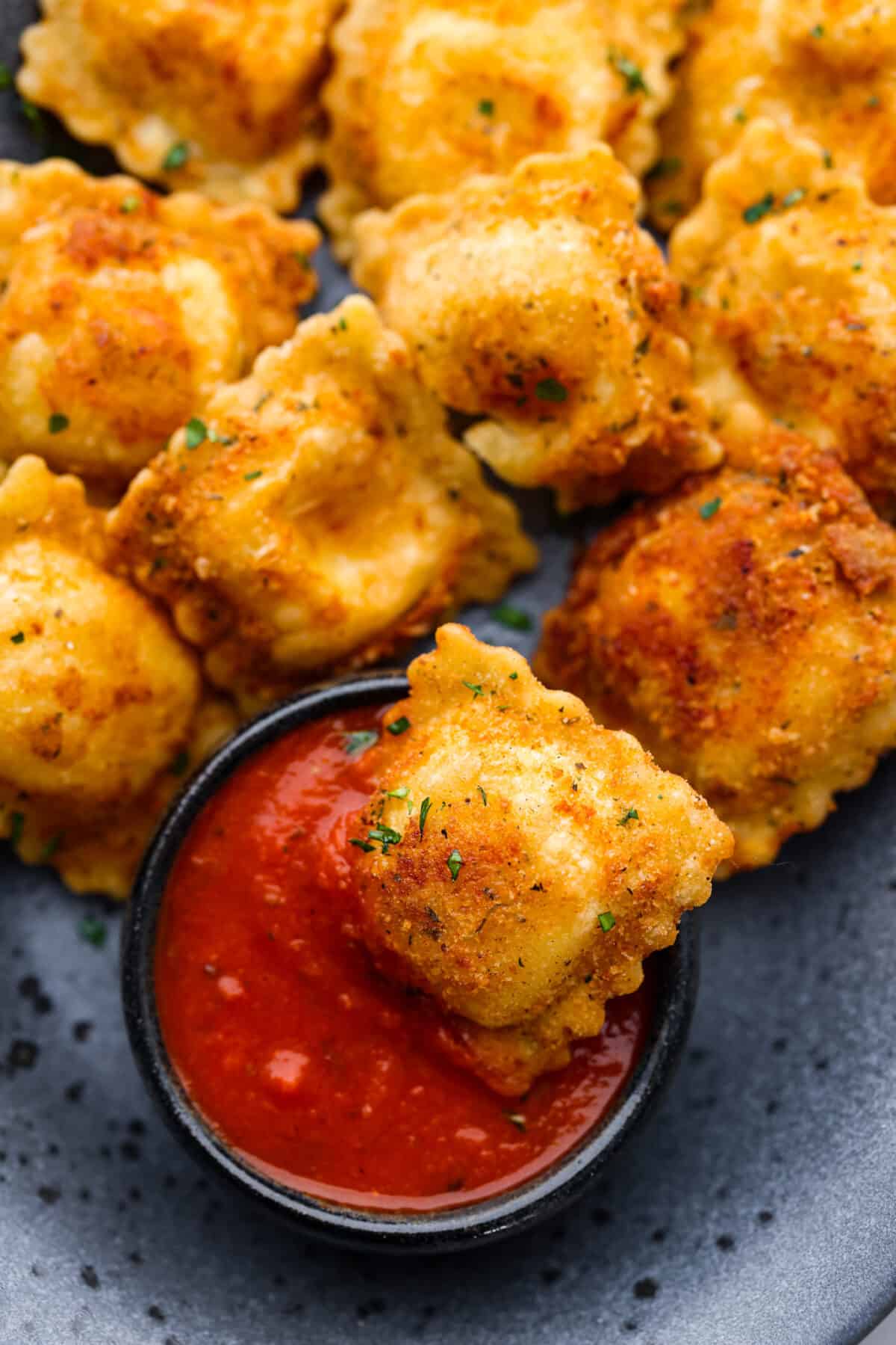 A ravioli being dipped into marinara sauce.