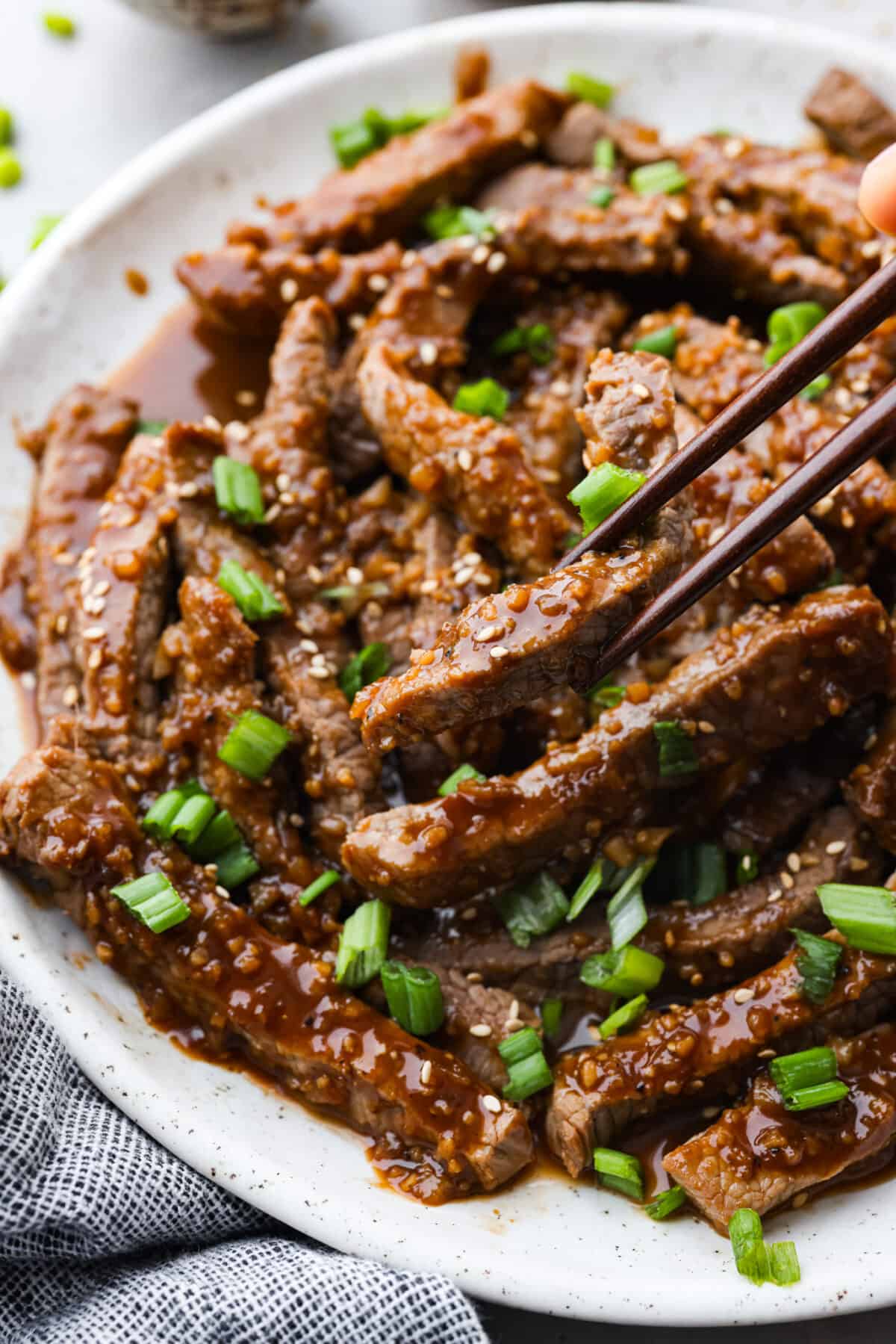 Closeup of bulgogi being picked up with chopsticks.