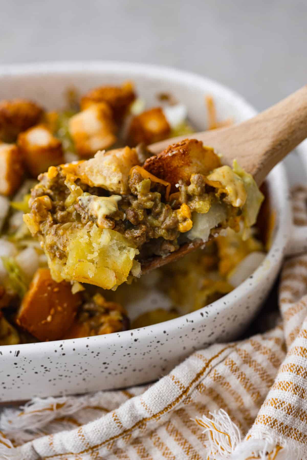 A scoop of casserole on a wooden spoon.