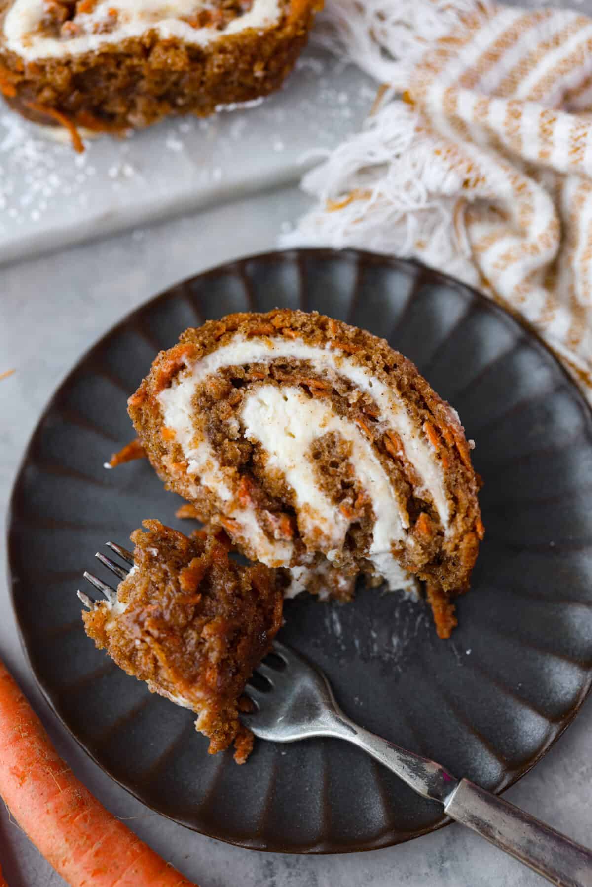 Taking a bite of cake that was served on a black plate.