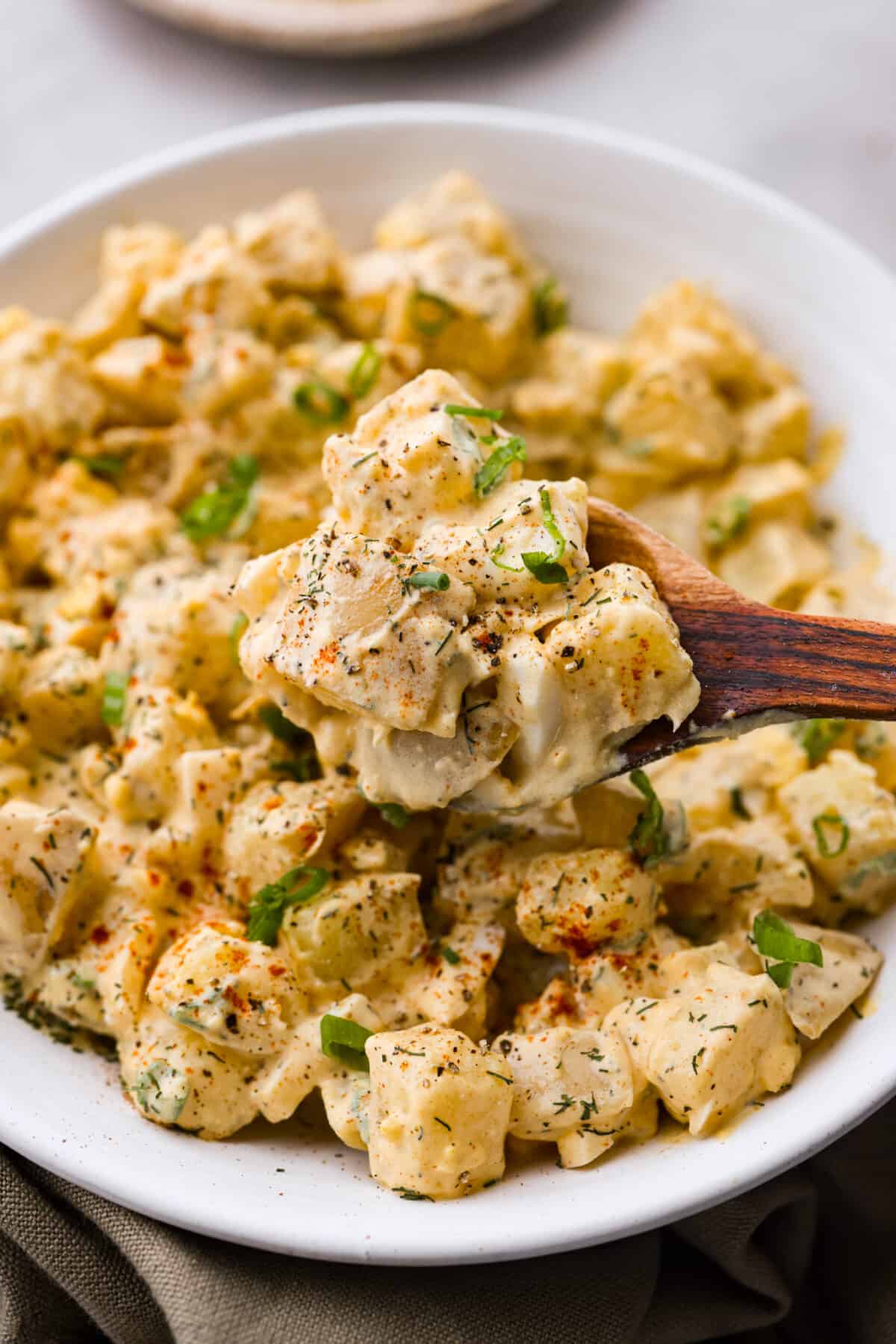 Closeup of potato salad on a wooden spoon.