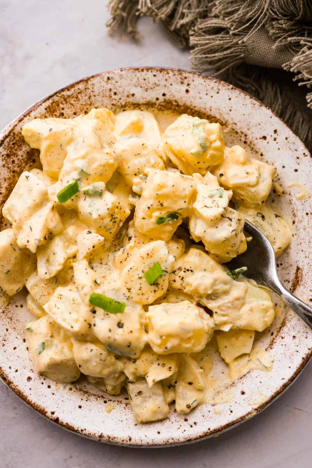 A serving of potato salad on a stoneware plate.