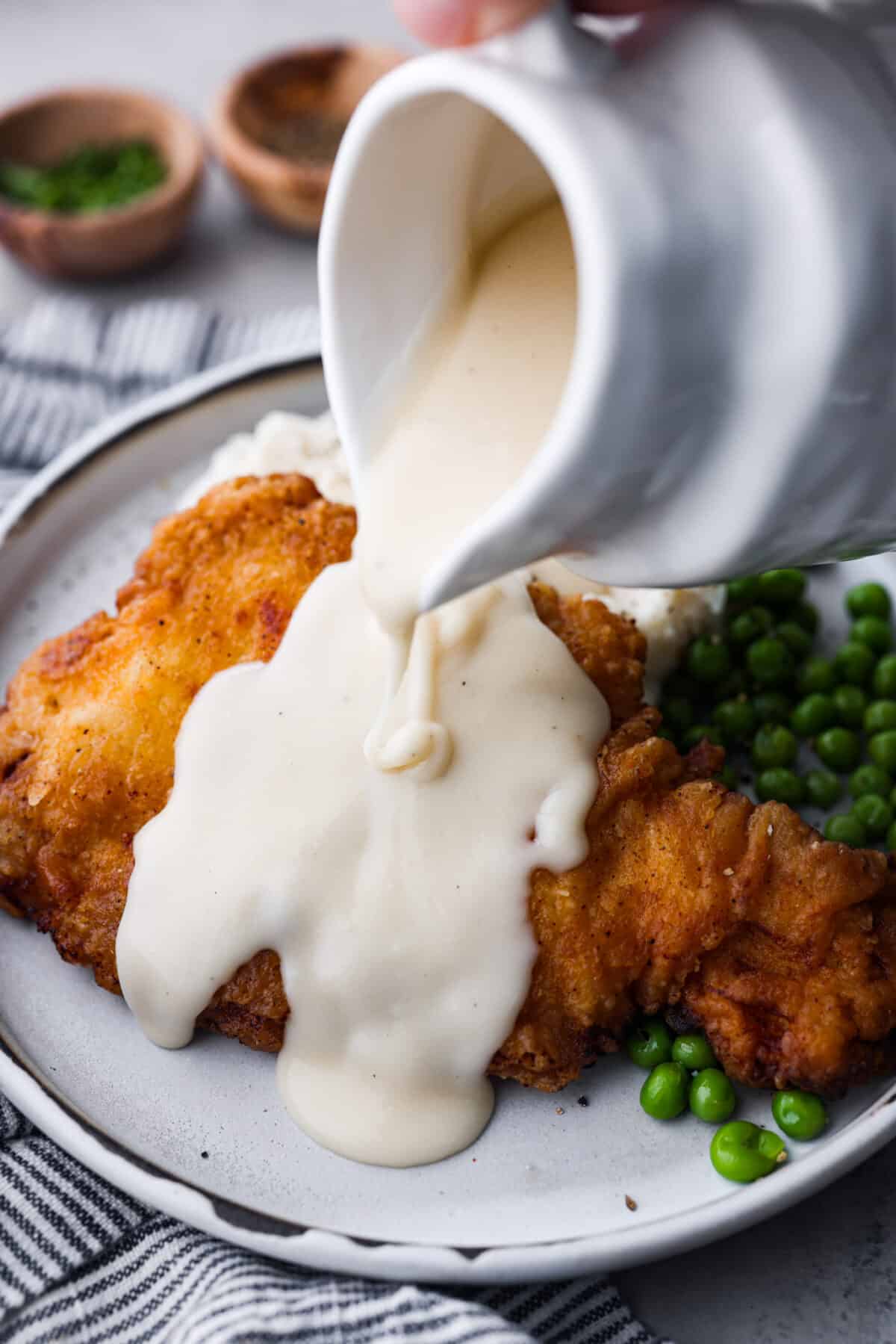 Pouring gravy over the chicken.