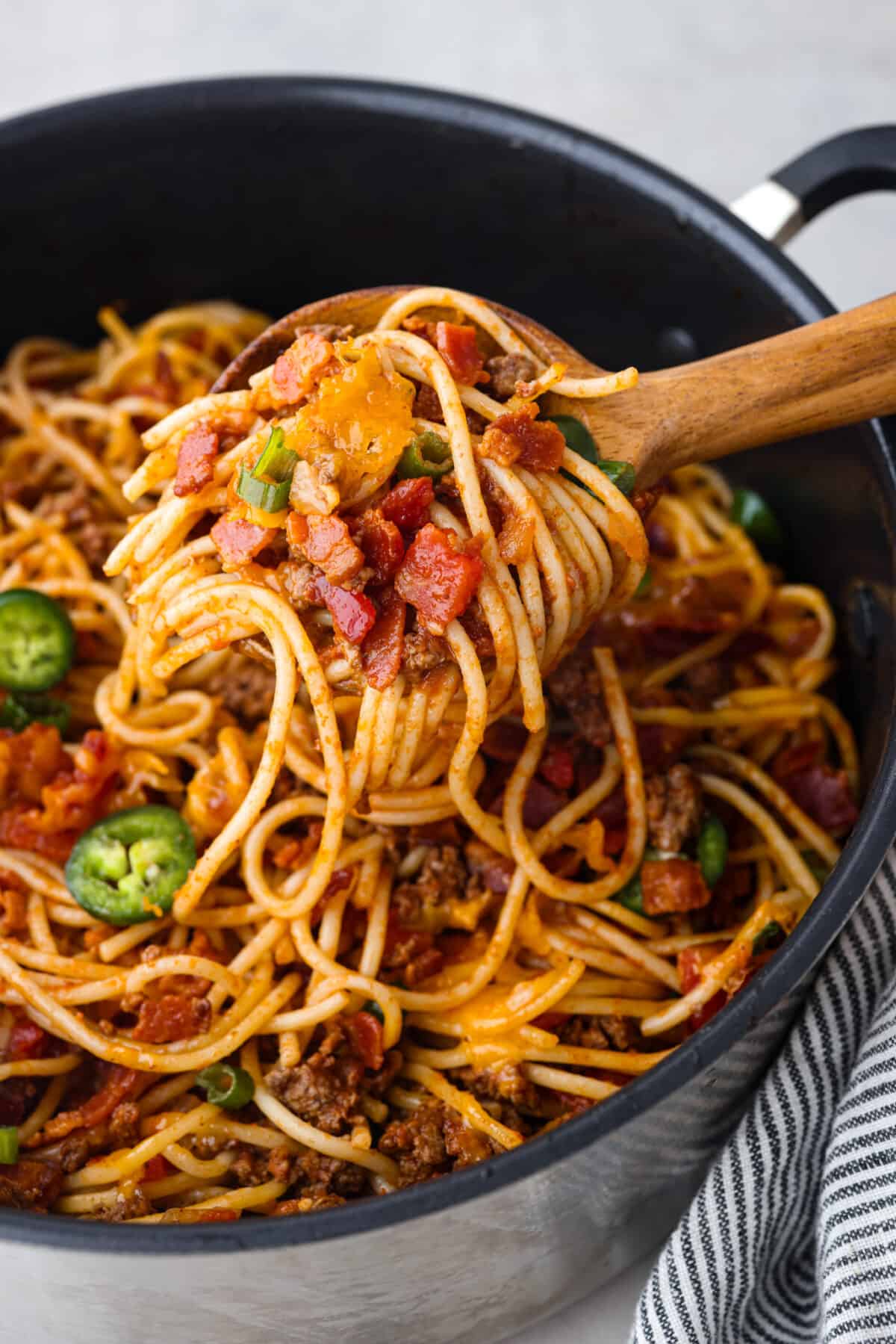 A scoop of spaghetti on a wooden spoon.