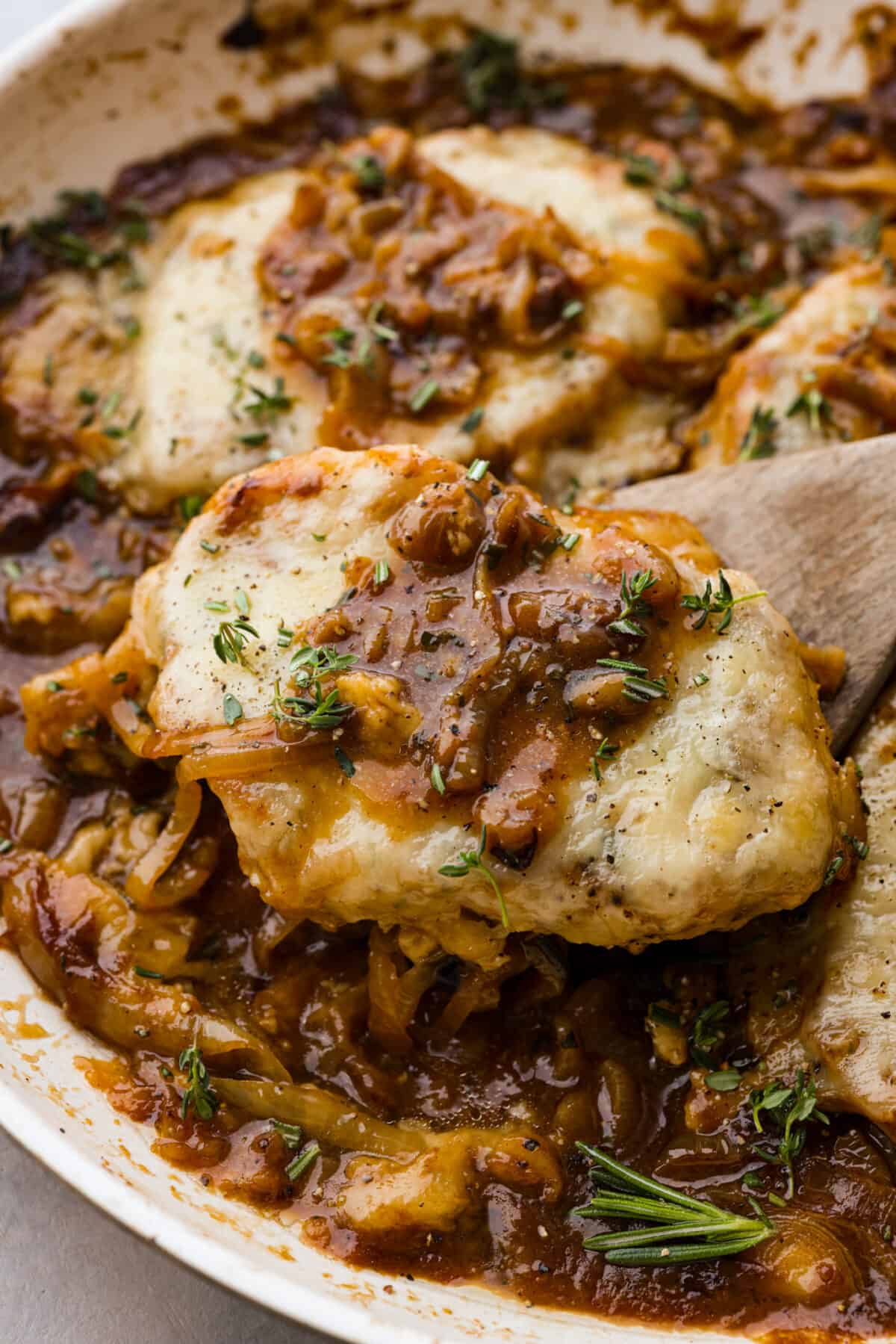 A French onion pork chop on a wooden spoon