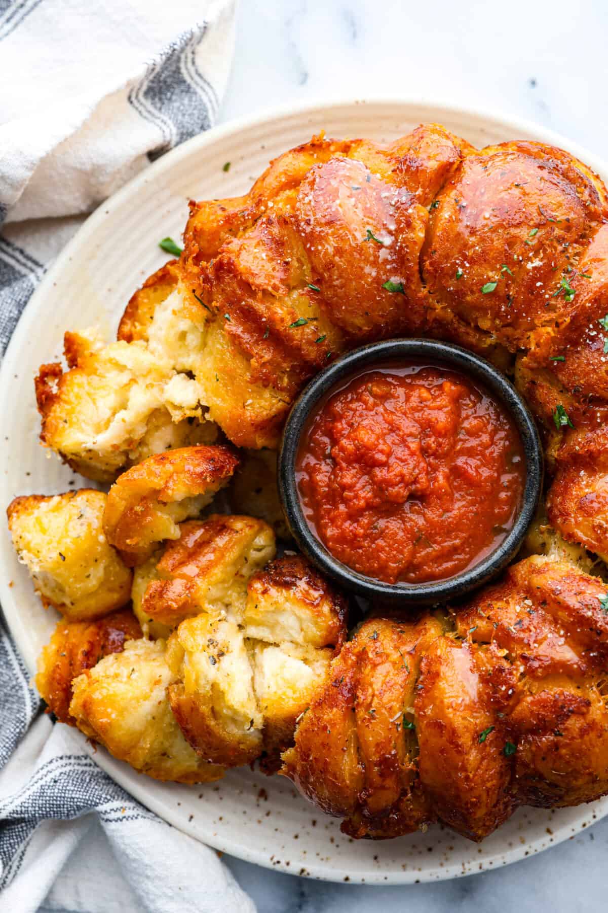 Garlic parmesan pull-apart bread served around a bowl of marinara.