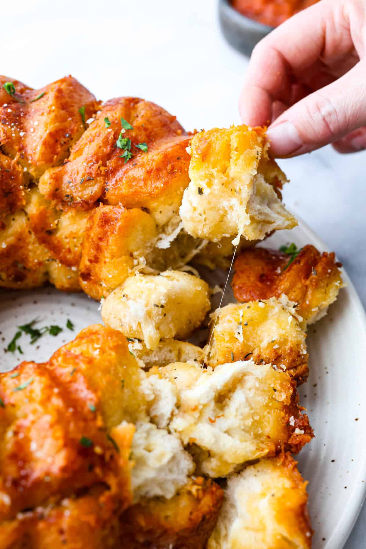 Picking up a piece of garlic parmesan pull-apart bread.