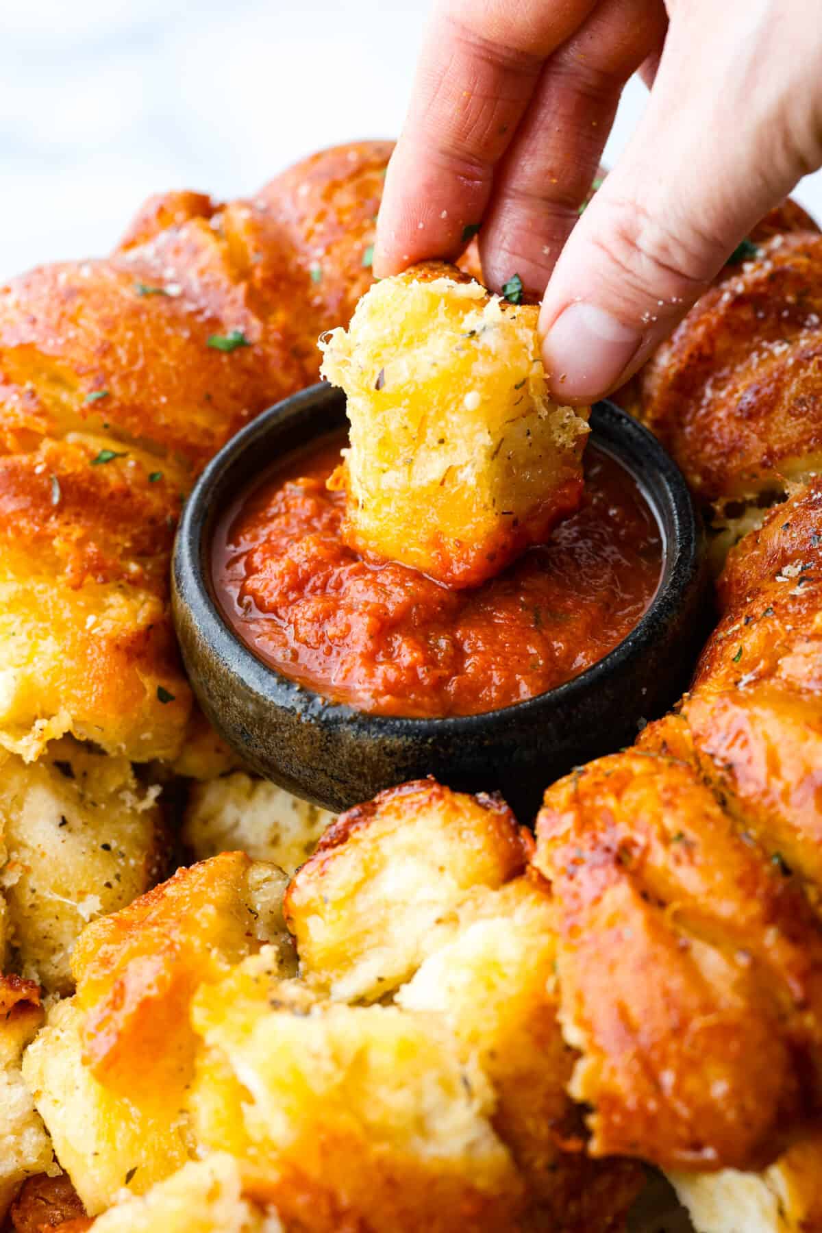 Dipping a cheesy roll into the marinara sauce.