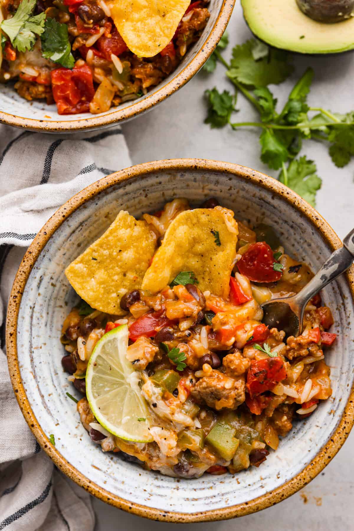 A serving of the taco skillet in a stoneware bowl topped with tortilla chips and a lime slice.