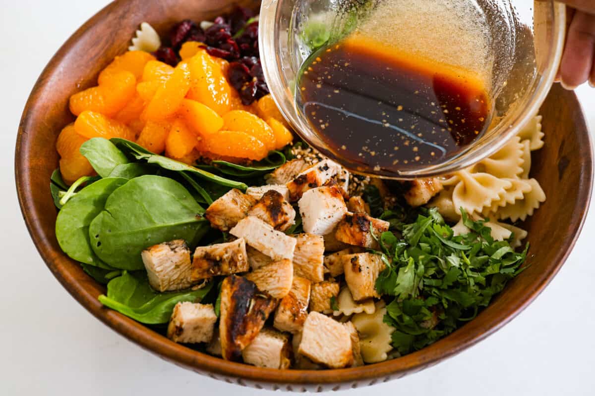 Adding the dressing to the teriyaki spinach pasta salad.