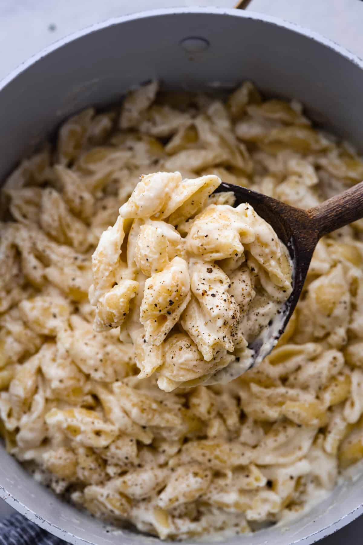 A scoop of white cheddar mac and cheese on a wooden spoon.