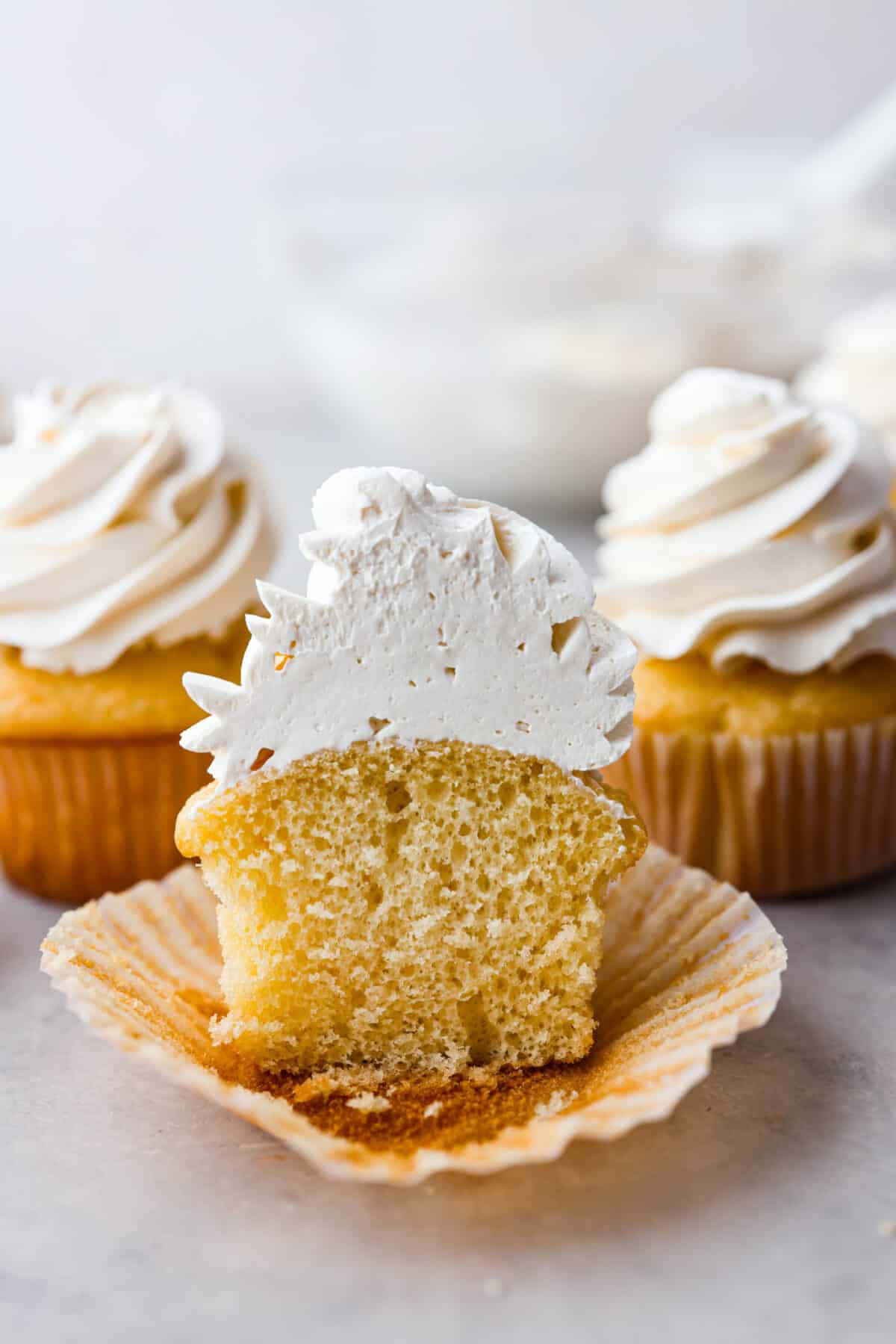 A cupcake frosted with Swiss meringue buttercream, cut in half.