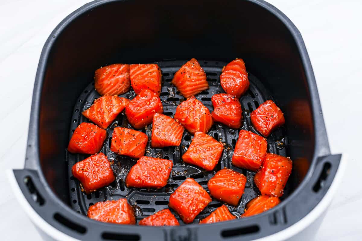 The marinated fish being added to the basket of an air fryer