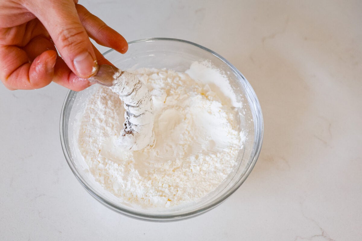 Shrimp being dipped in cornstarch. 