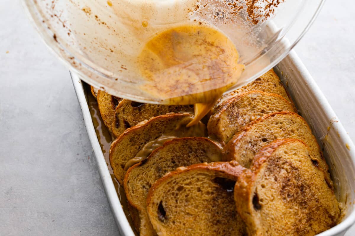 Pouring the remaining egg mixture over the bread slices.