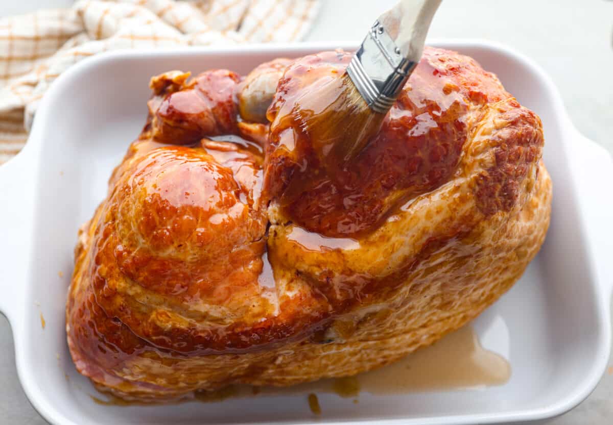 Basting the honey glaze over the ham.