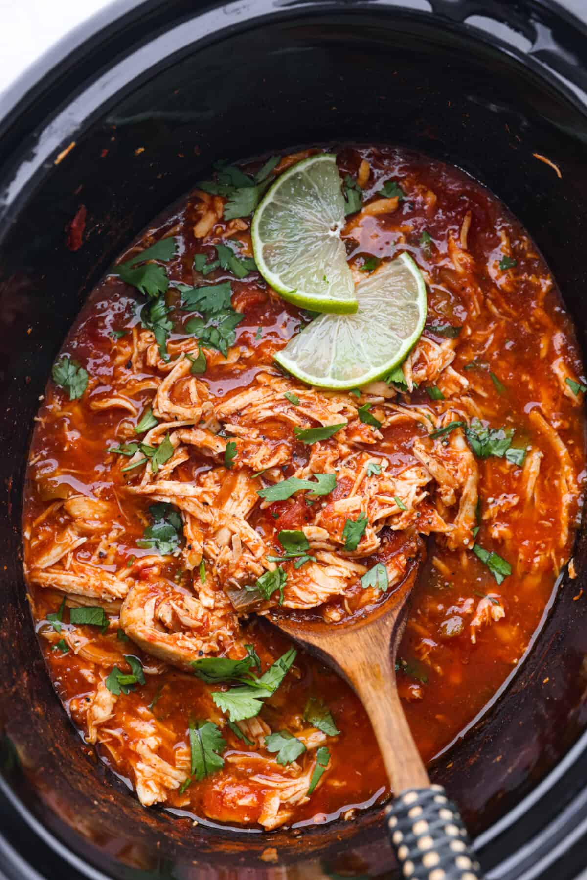 Top view of salsa chicken in the crockpot with a serving spoon.