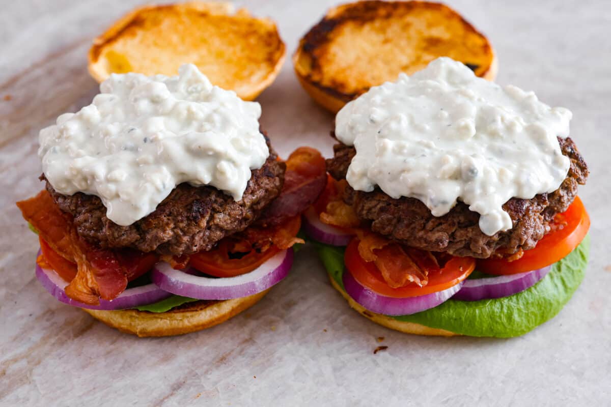 Side view of blue cheese burgers with all of the toppings without the top bun. 