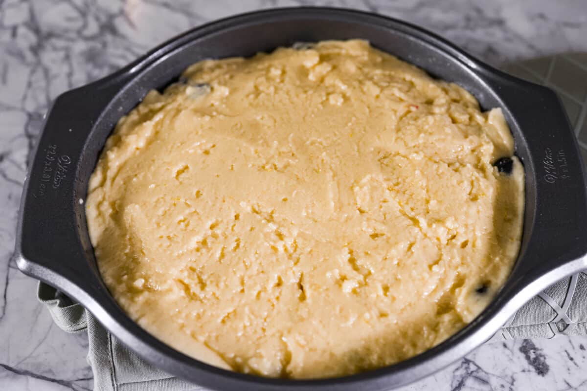 Fourth photo of the cake batter spread on the blueberry mixture.