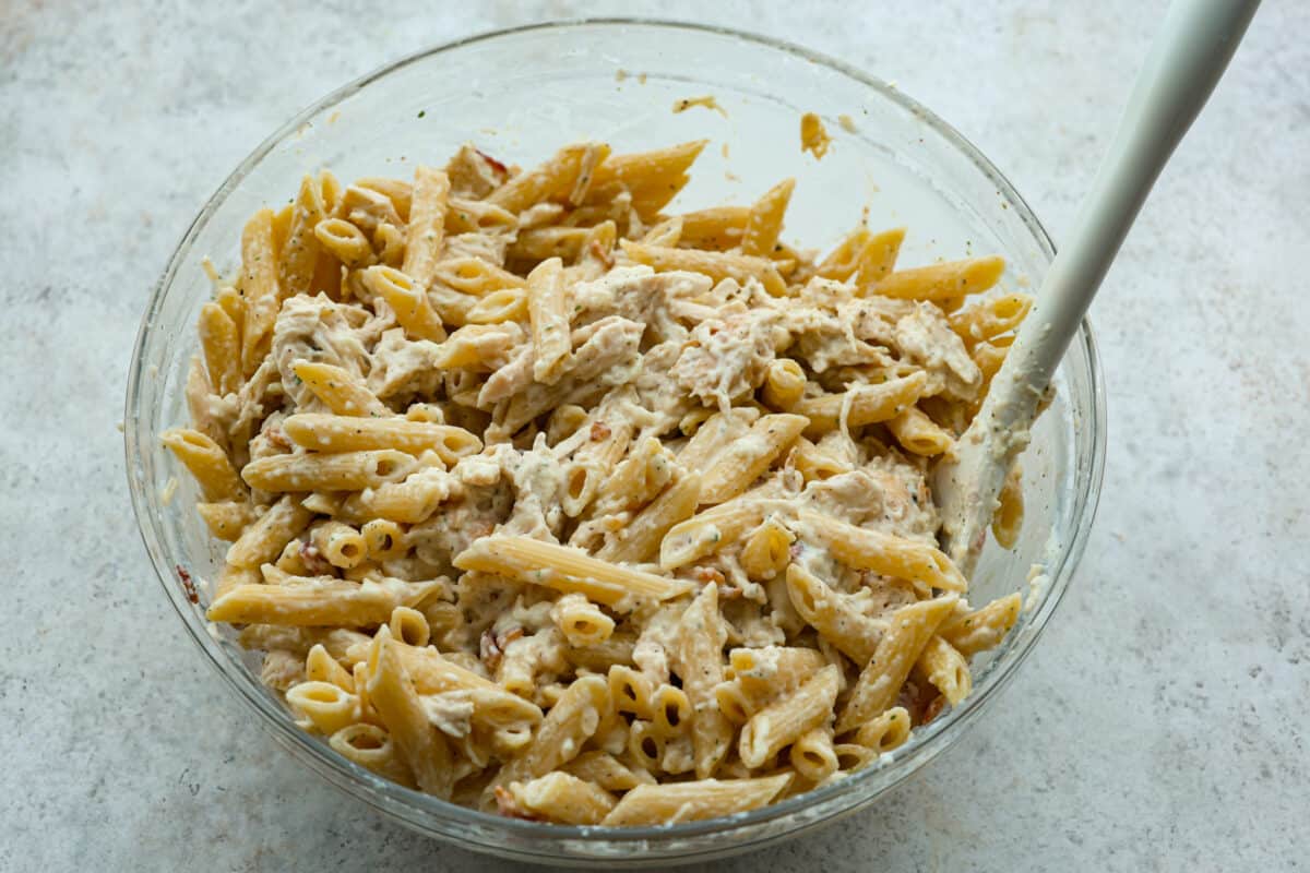 The pasta being added to the chicken mixture. 