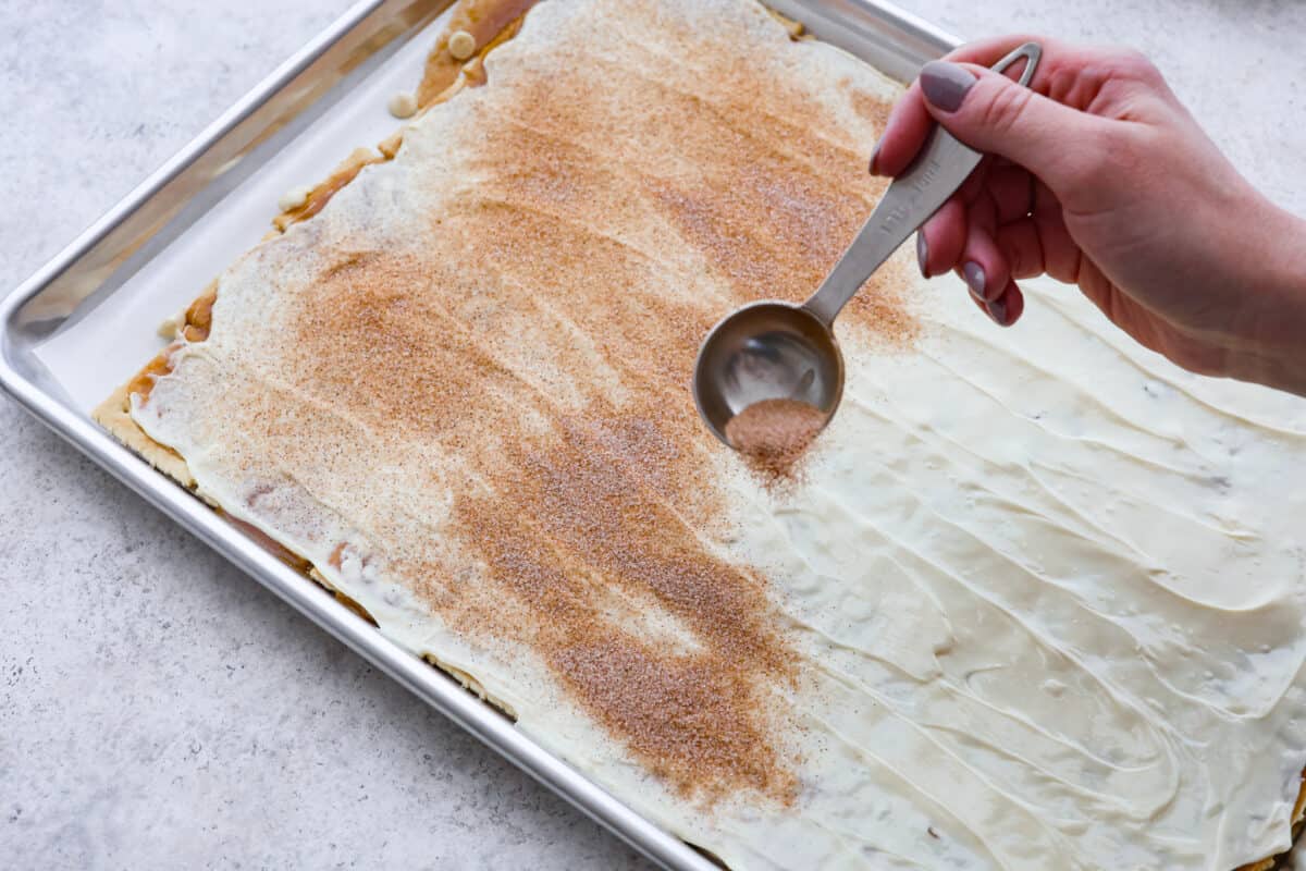 Cinnamon and sugar being sprinkled on churro crack. 