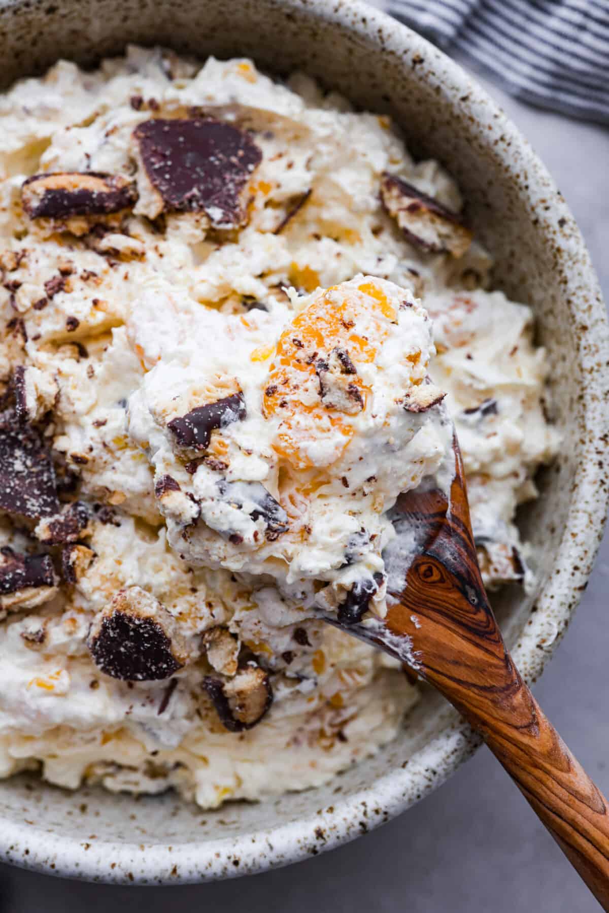 Close view of a wood serving spoon lifting up a spoonful of cookie salad.