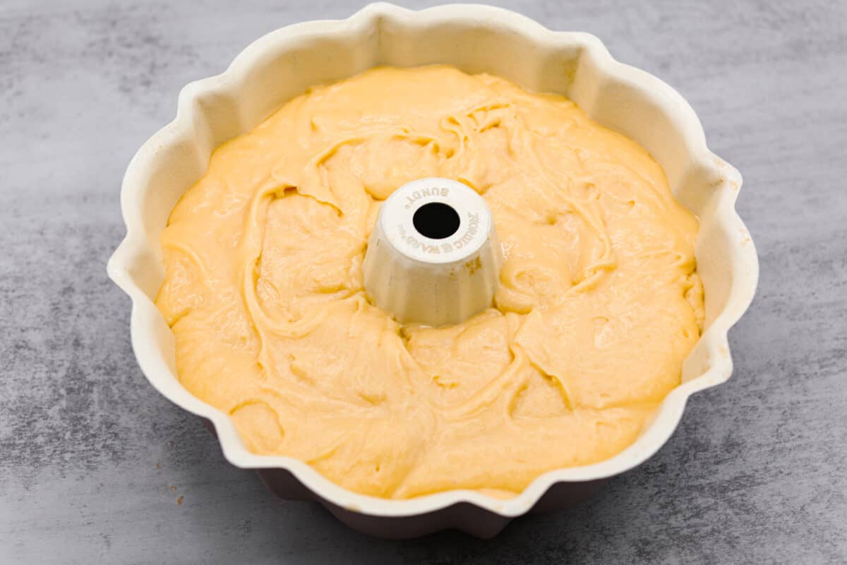 Pouring the cream cheese pound cake batter into a bundt pan.