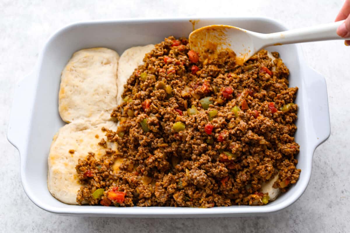 The meat mixture being added to the pressed biscuits. 