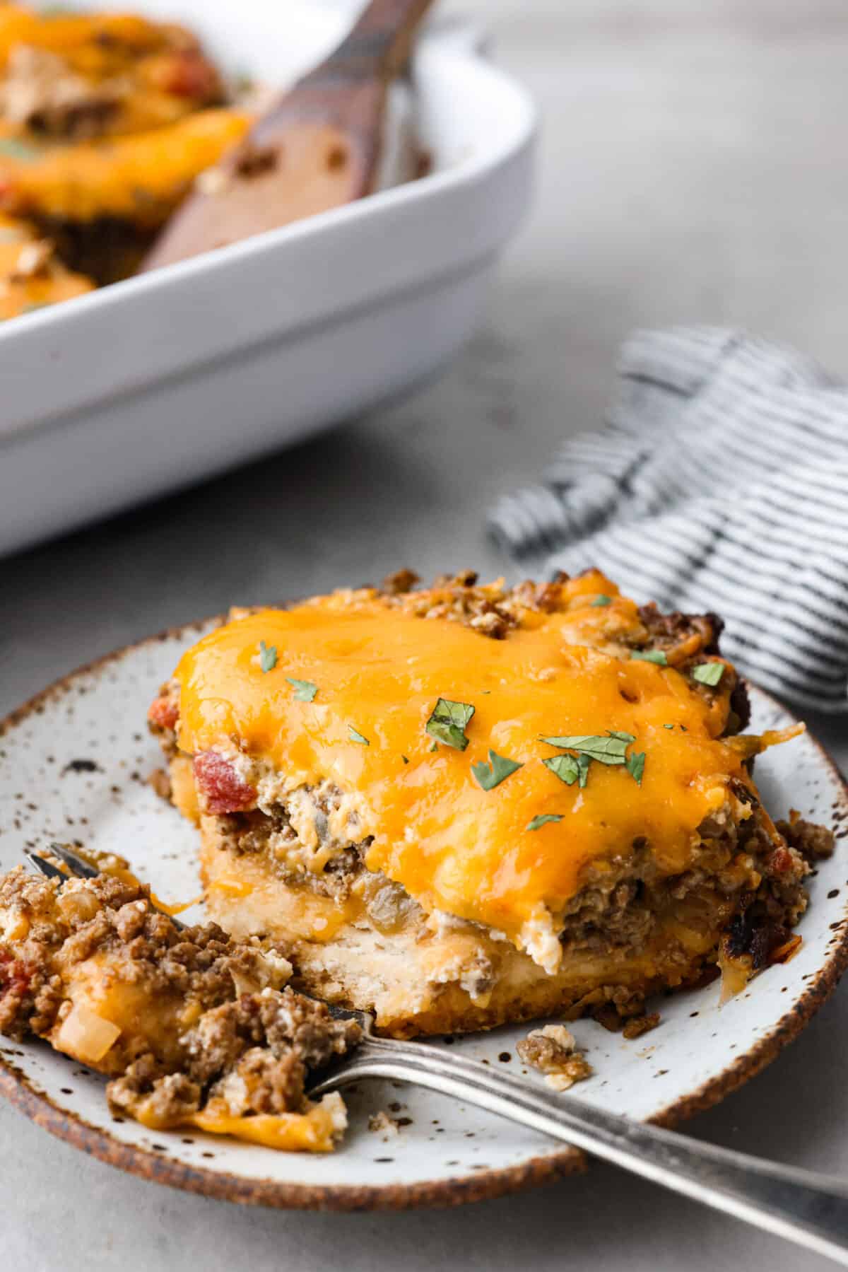 A square serving of John Wayne Casserole on a plate with a fork. 