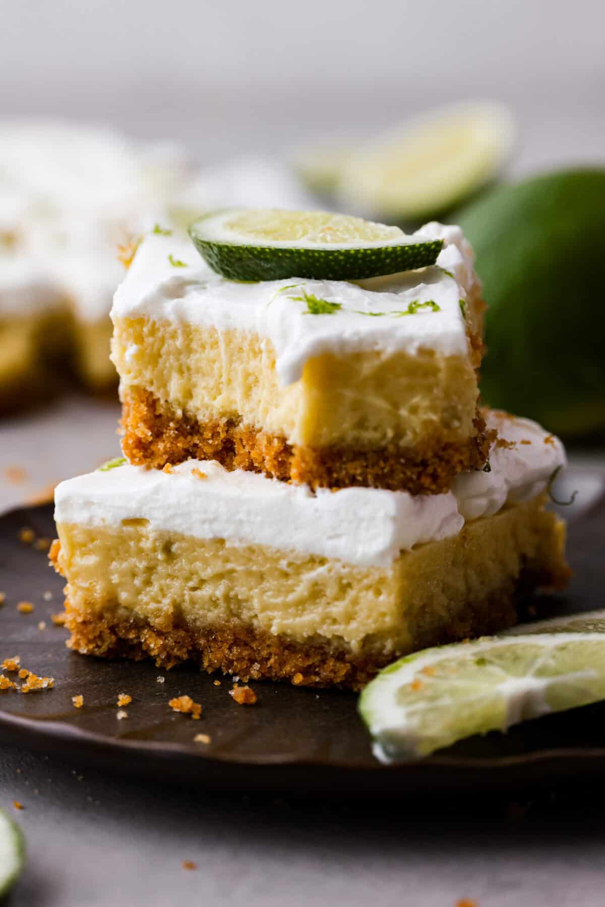 Close view of key lime pie bars stacked on a brown plate.