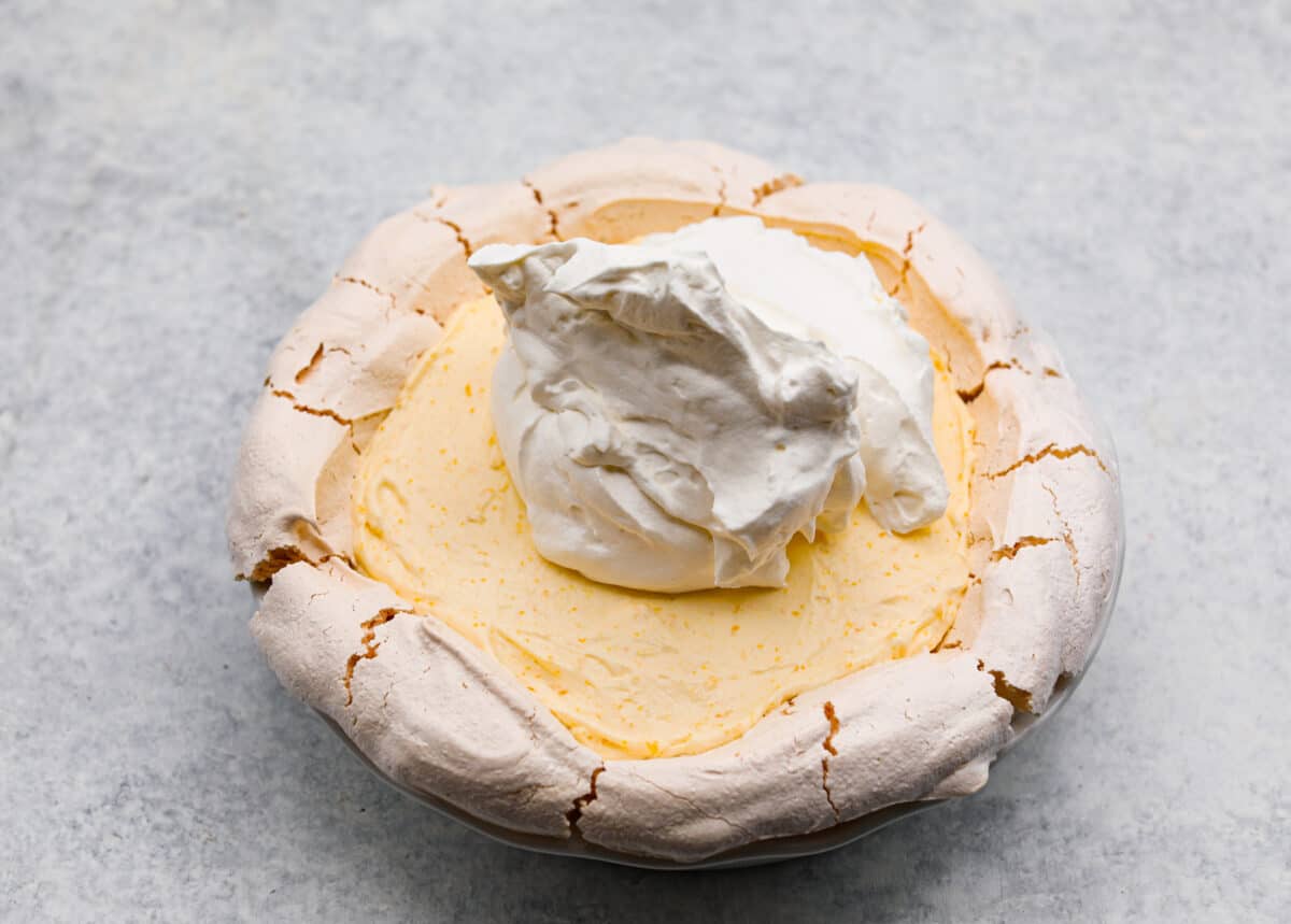 Sixth process photo of the remaining whipped cream being spread on top of the lemon angel pie.