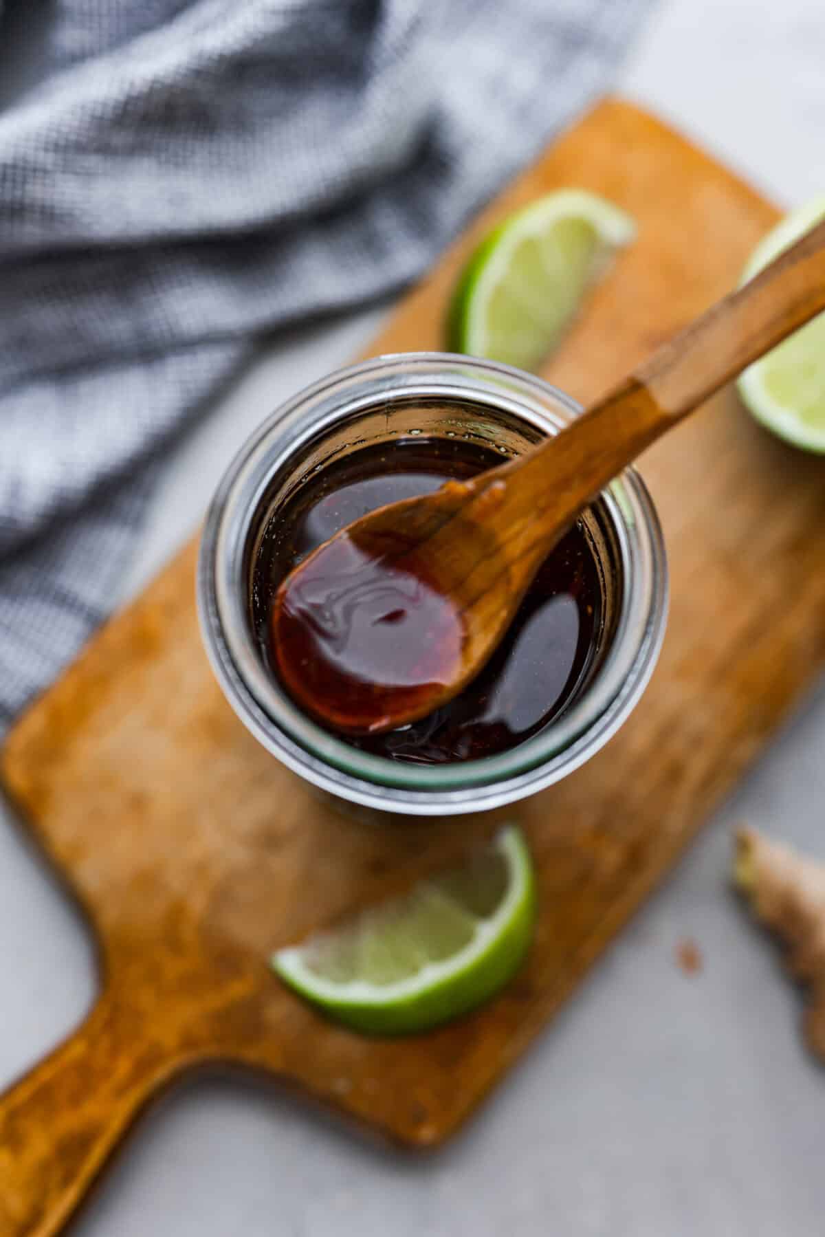 Overhead shot of a wooden spoon dipping into jar of poke sauce. 