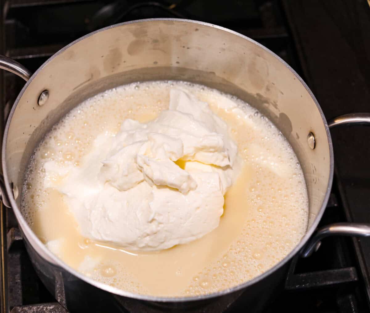 Overhead shot of silver pot with boiled mixture with pile of sour cream in the middle. 